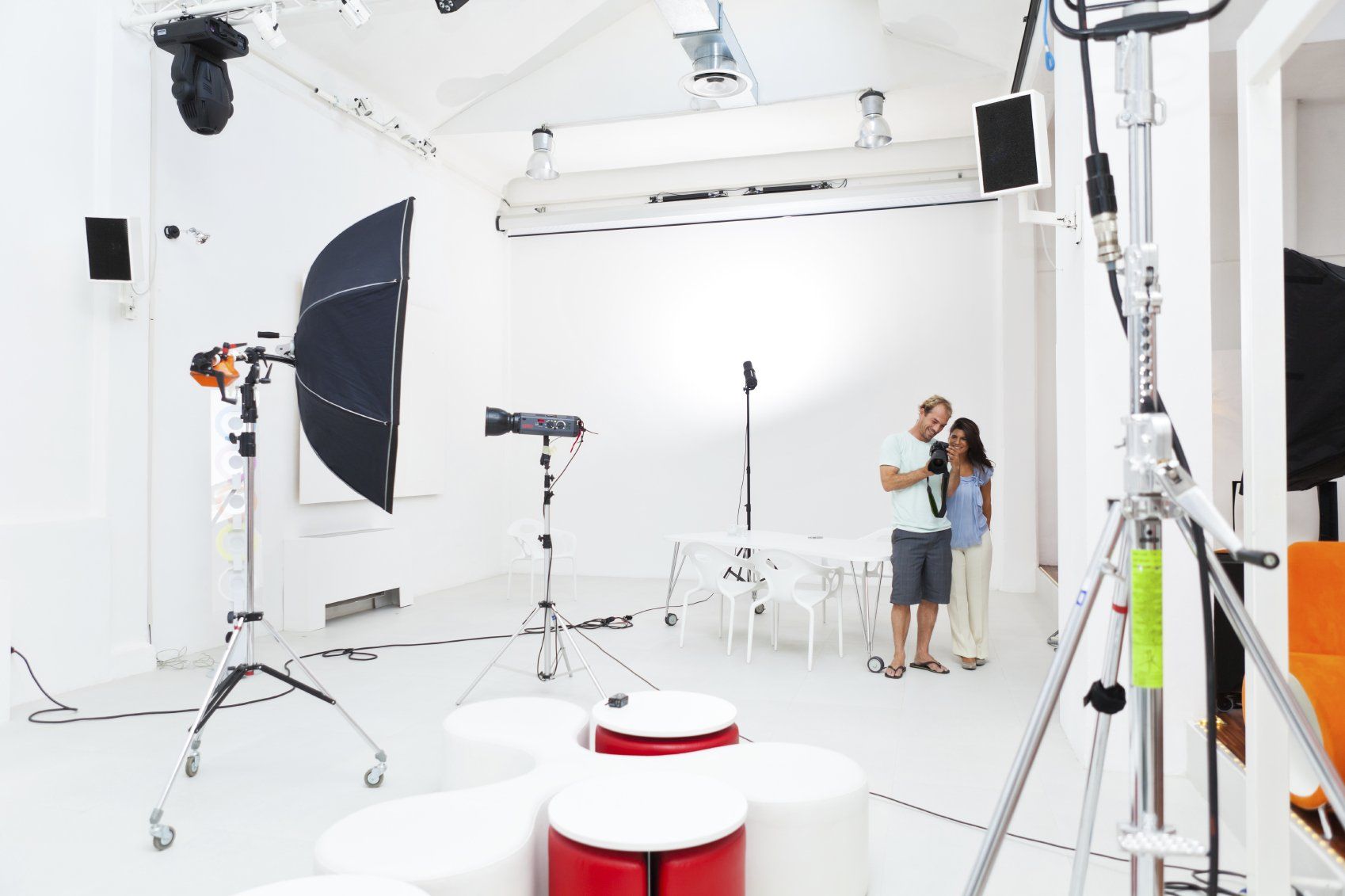 Photographer and client in a photo studio with many lights on light stands.