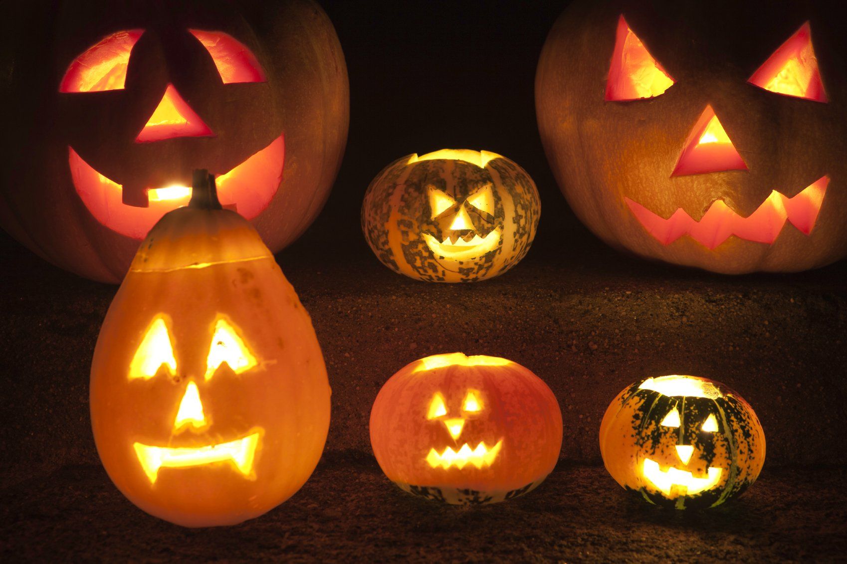 Kürbisse sind zu Halloweenmonstern geschnitzt und leuchten im Dunkeln