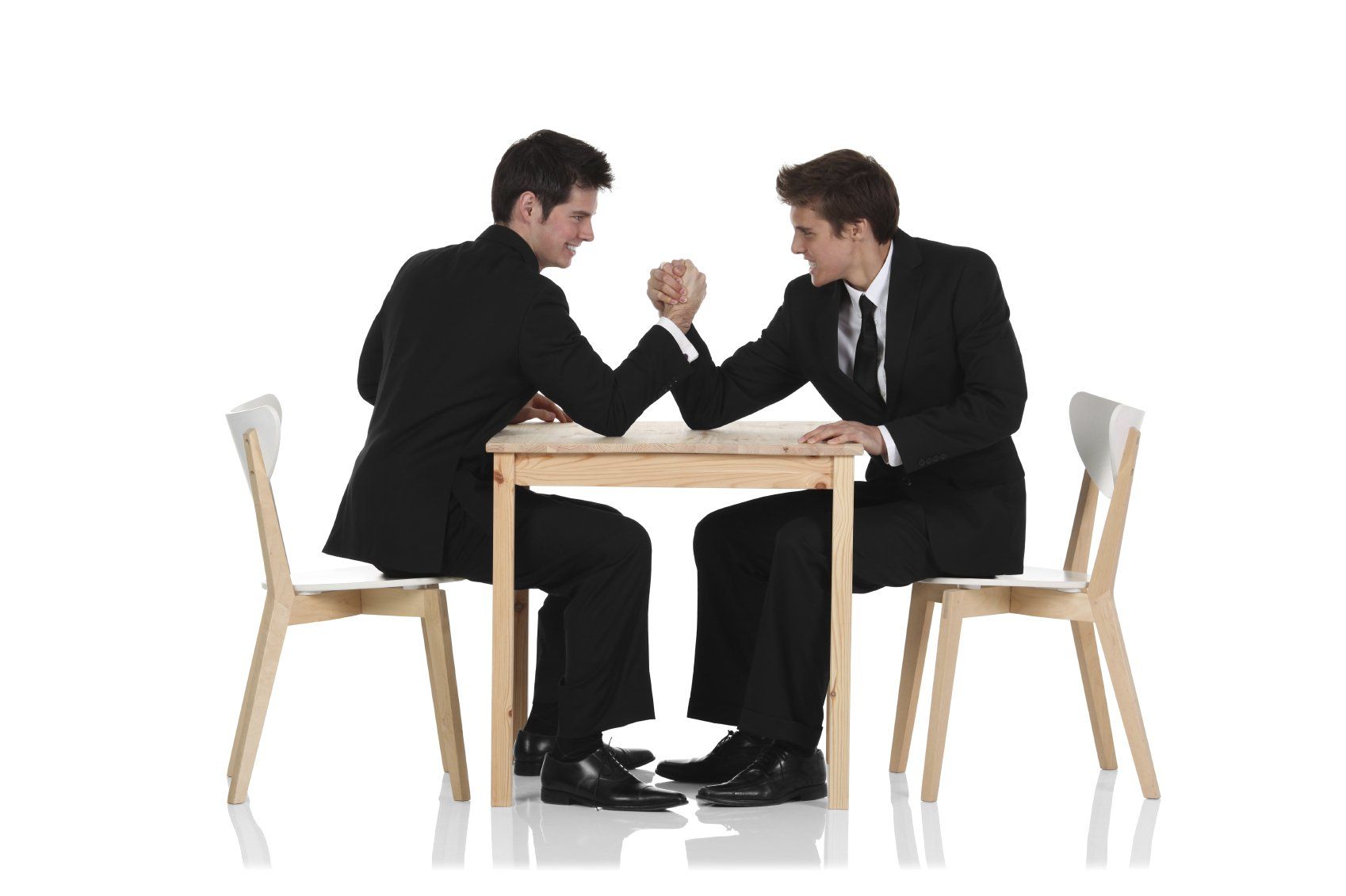 Zwei Männer in Geschäftsanzügen liefern sich an einem Tisch einen Armdrücken-Kampf, begleitet von einem auf deutsch-italienische Mediation spezialisierten Mediator
