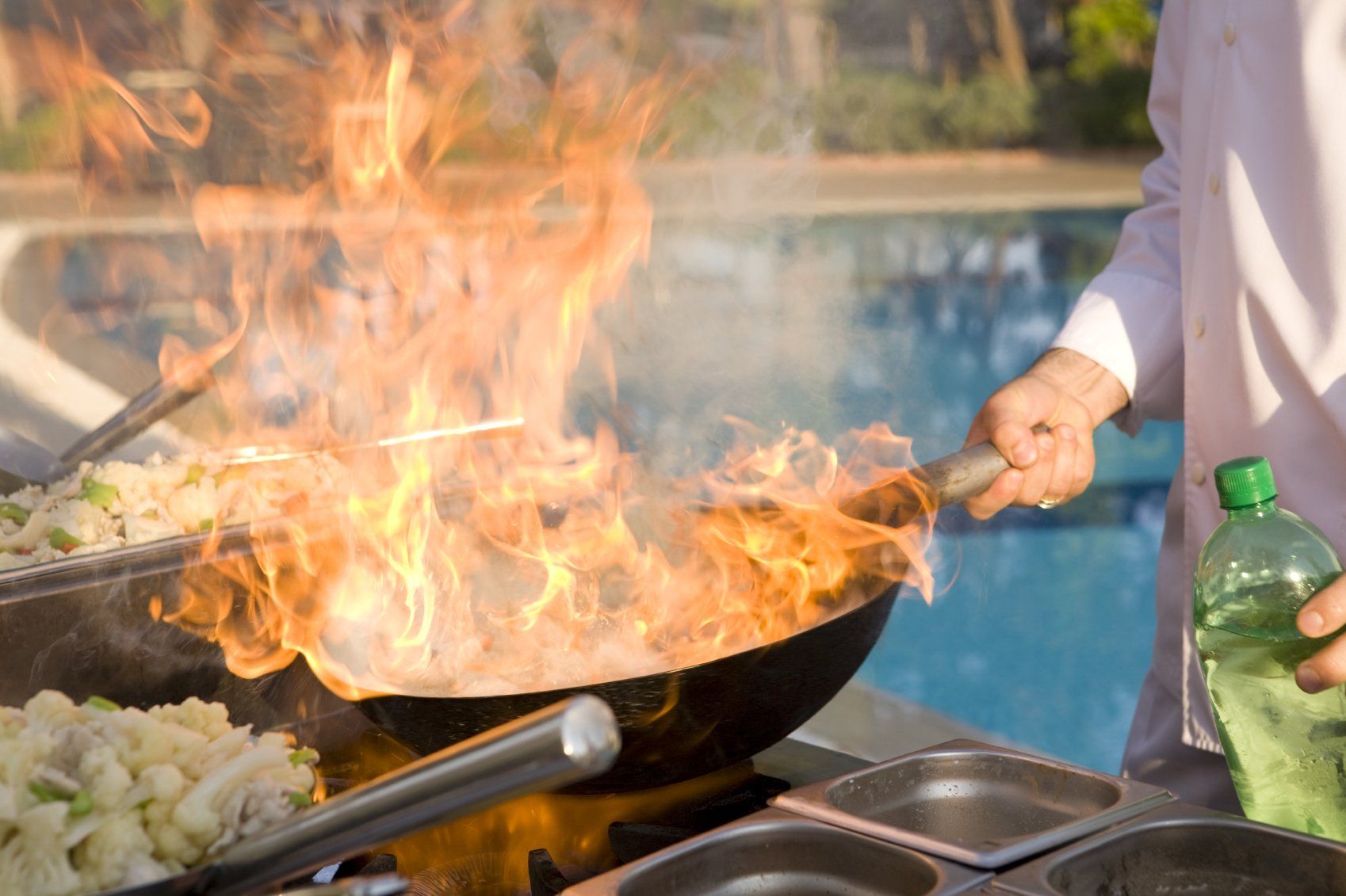 A cook uses the flambe method in a wok.