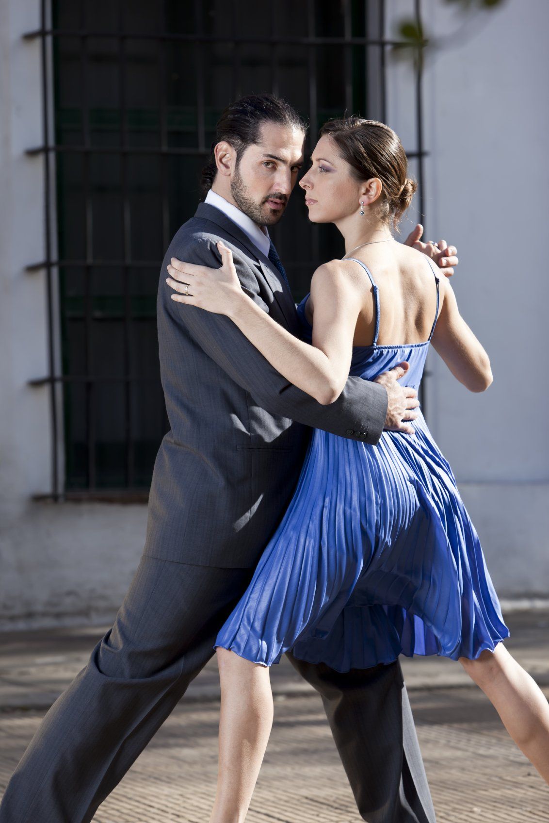 Young man in grey suit, dancing tango with young lady in blue dress