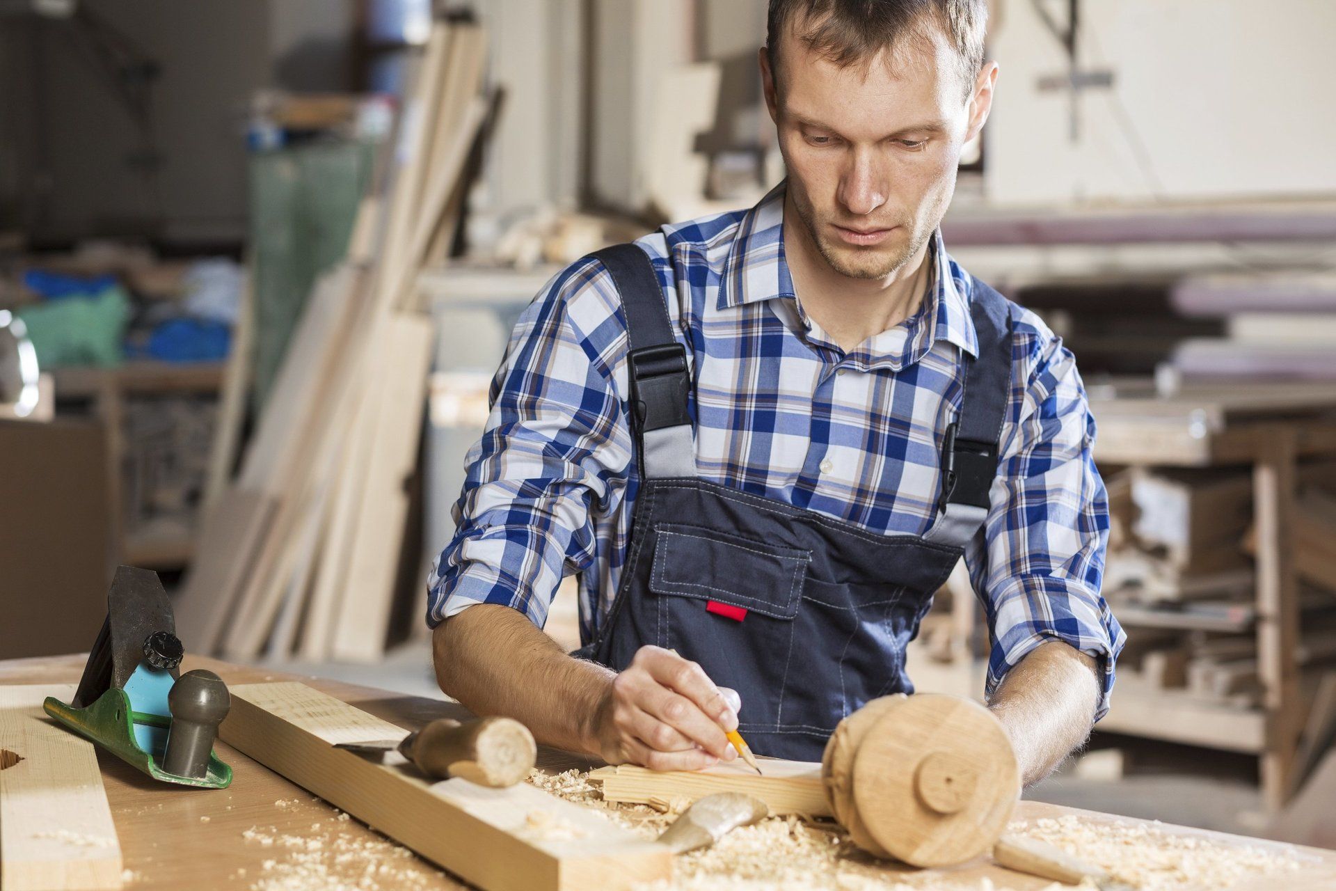 A woodworker in a checkered shirt working in his workshop