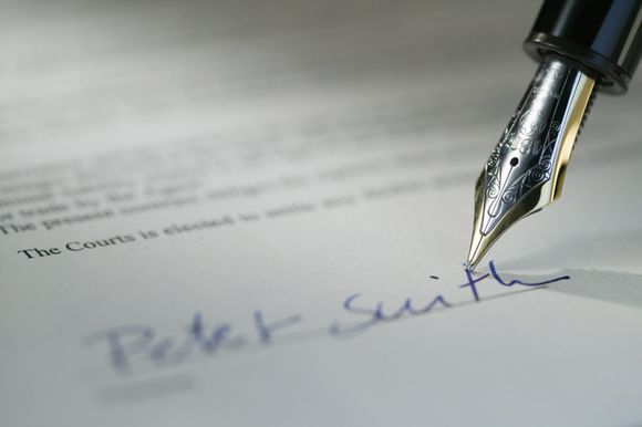 a signature being signed on paper