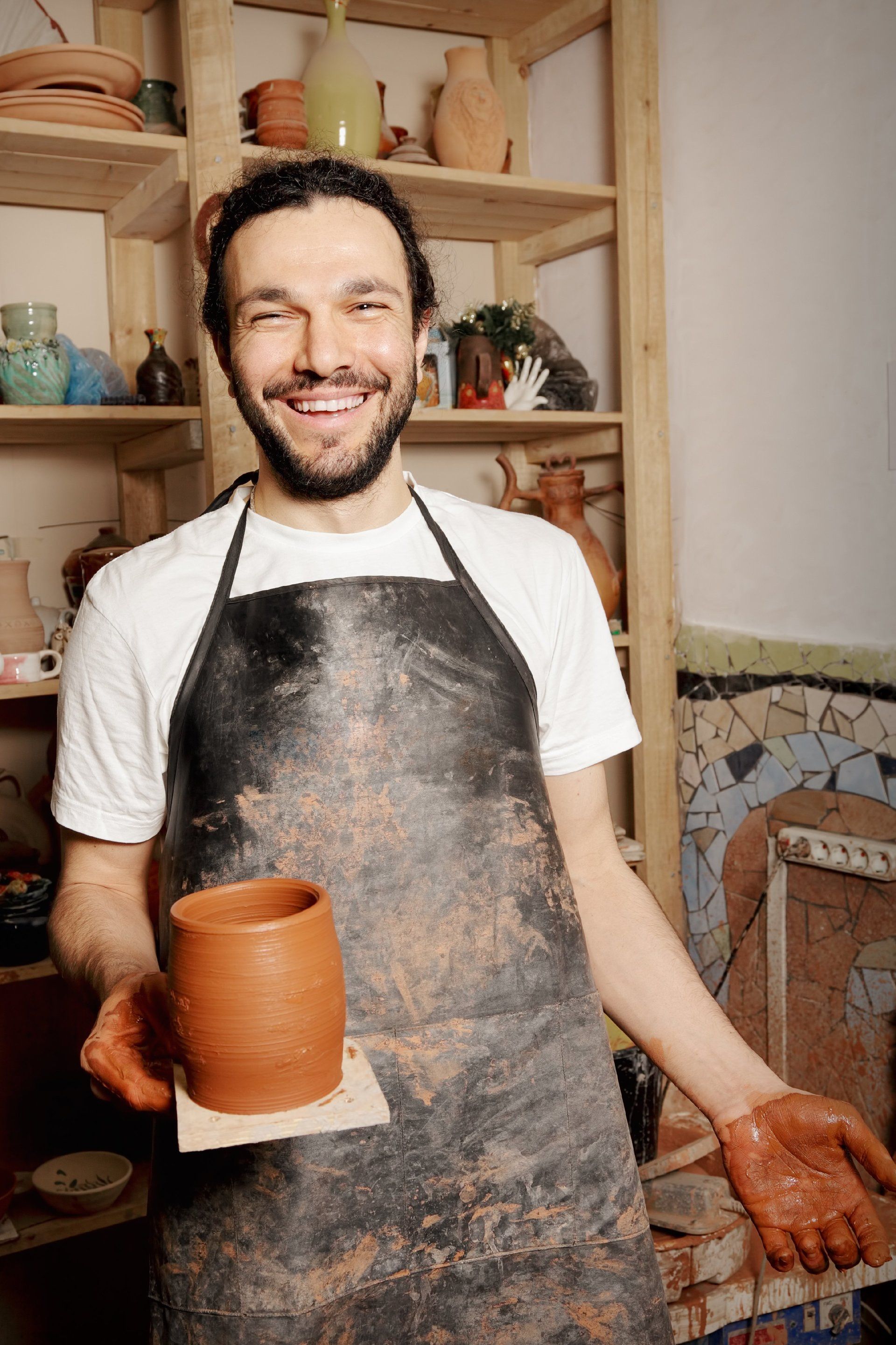 Pottery maker in his shop standing proud with his finished product in hand