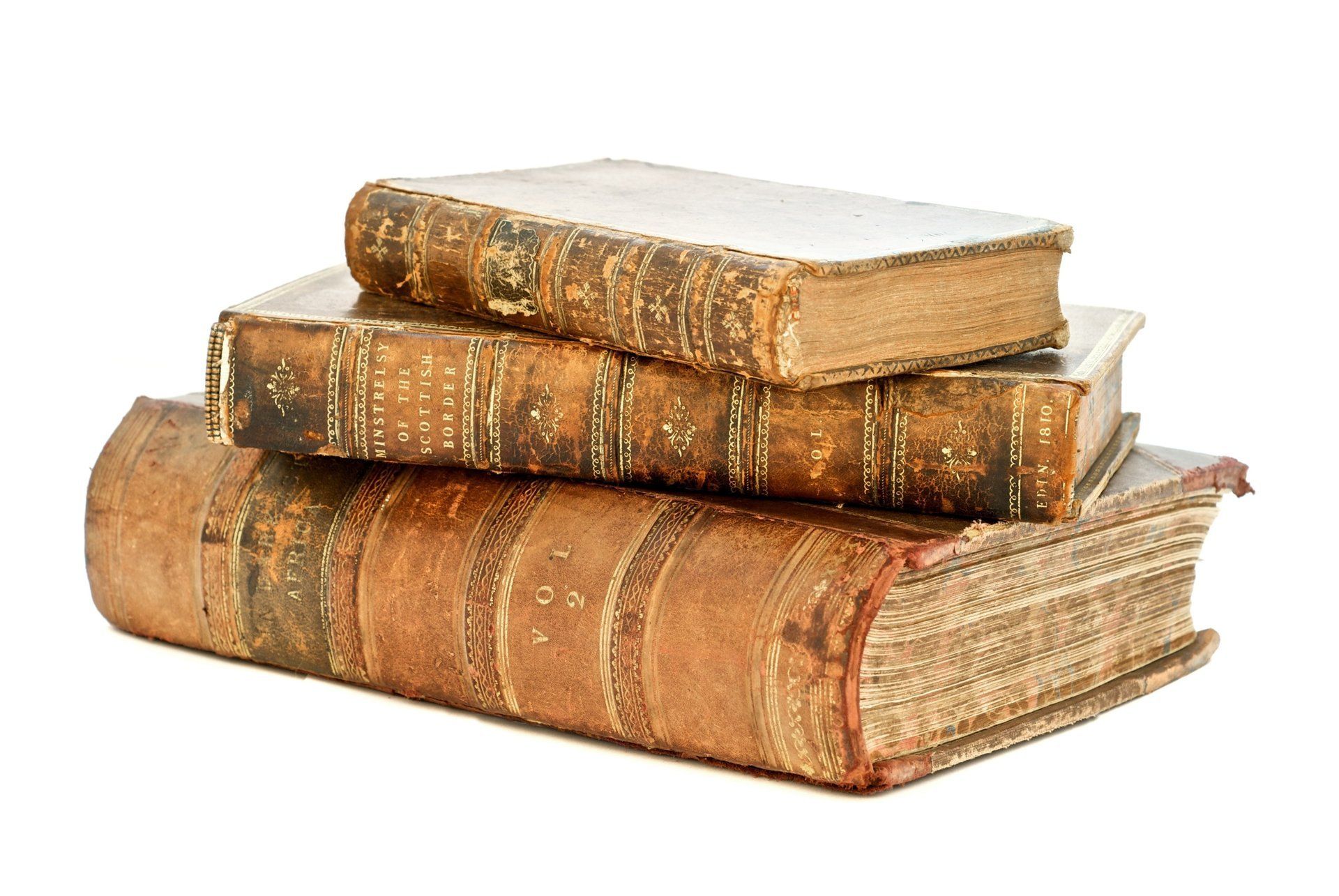 Three ancient-looking books sitting on a white surface