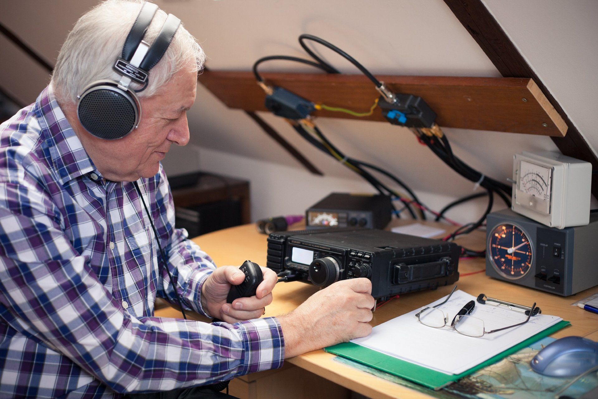 An elderly man operating a communications radio on a yacht.