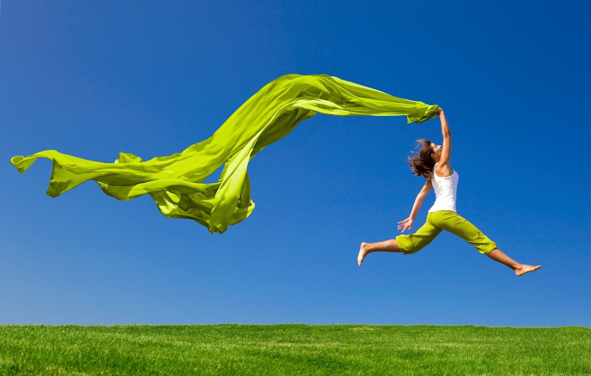 Woman skipping across a field with a silk scarf floating behind her