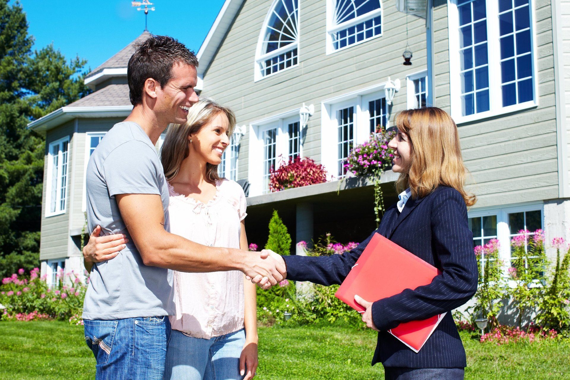 Eine Immobilienmaklerin steht vor einem Haus mit Ihren Kunden