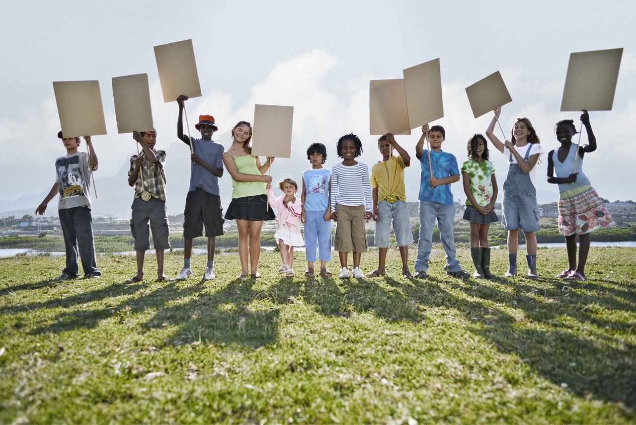 Kinder mit Schildern in der Hand stehen auf einer Wiese