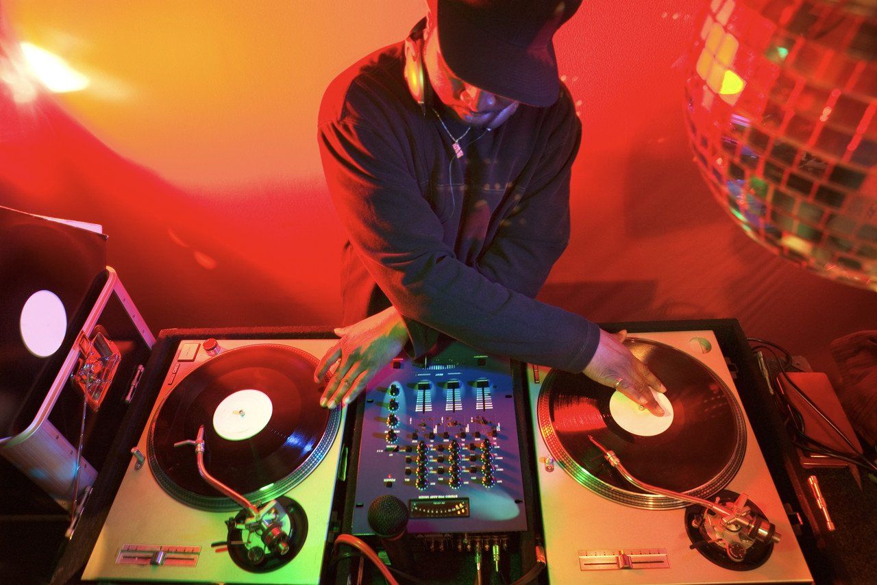 Ein DJ legt Musik auf, während er an seinen Turntables arbeitet.