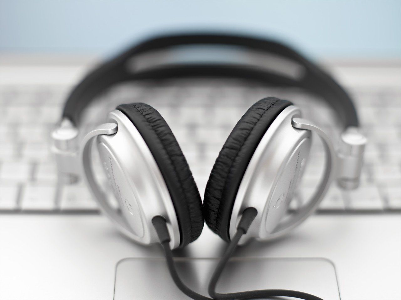 Lifelong Learning.  A pair of silver headphones sitting on a keyboard.