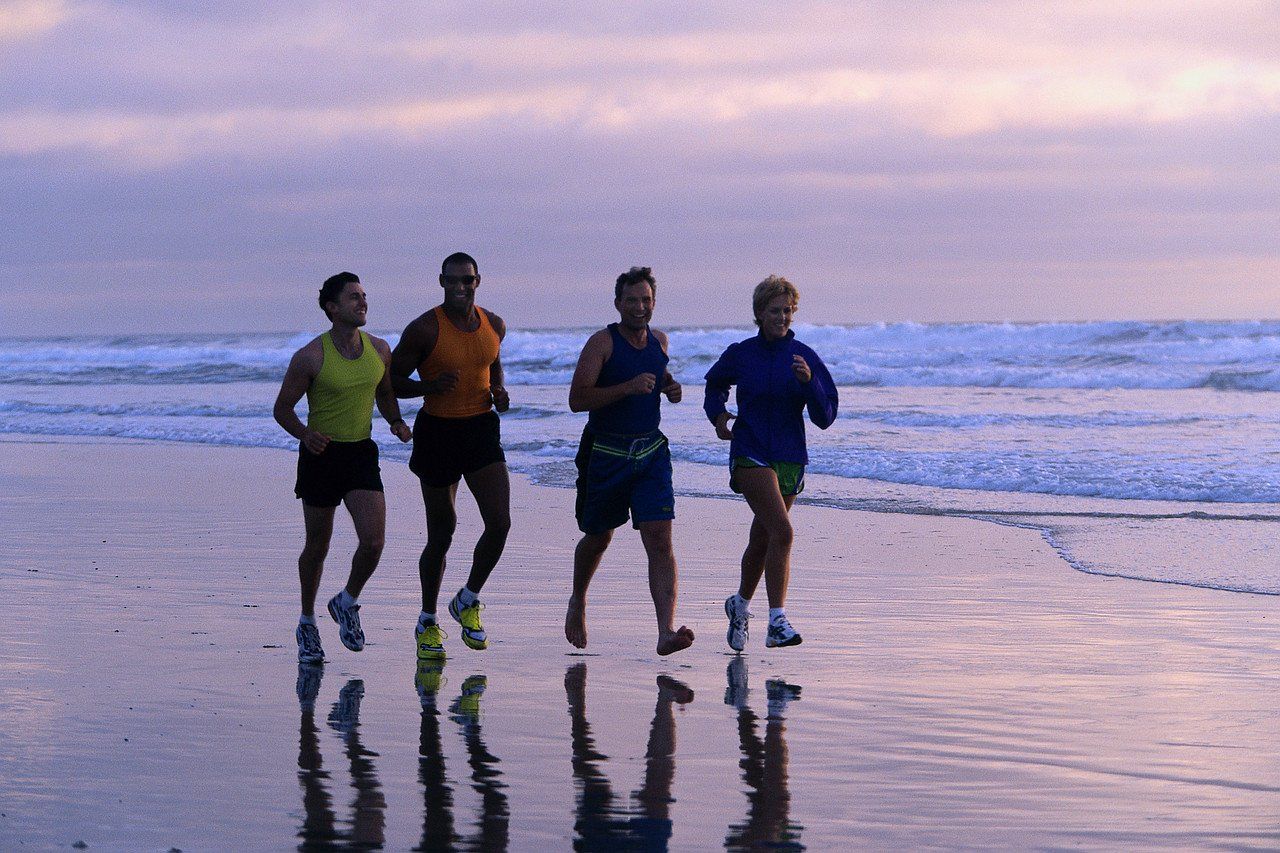 Four men jogging on the beach