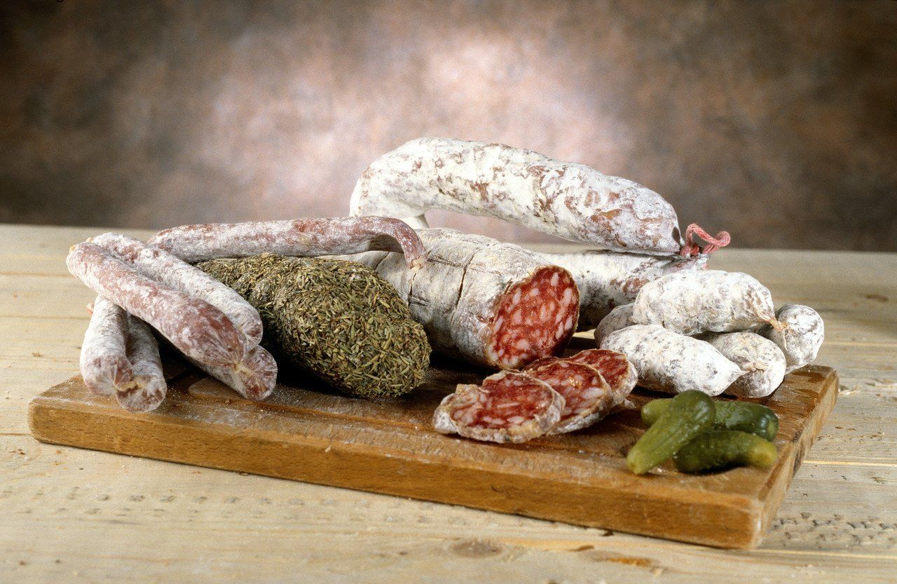 Frozen sausages and pickles sitting on a wooden cutting board