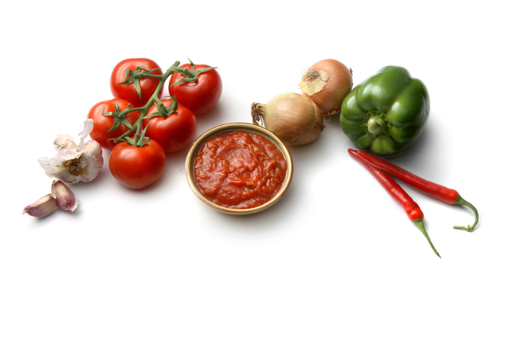 A cluster of tomatoes, onions, garlic and salsa on a table.