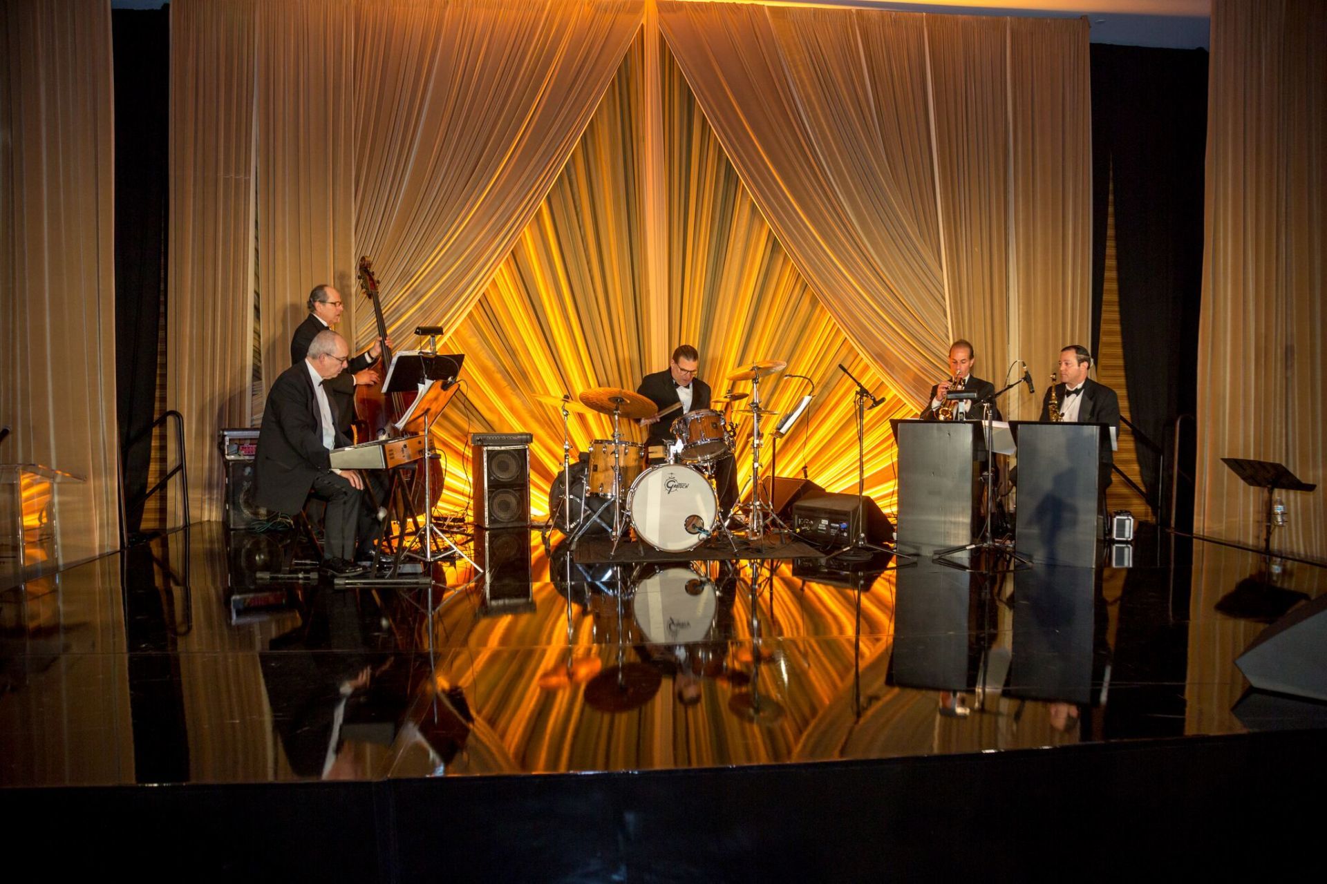 An image of musicians performing on a stage with elaborate draping behind them.