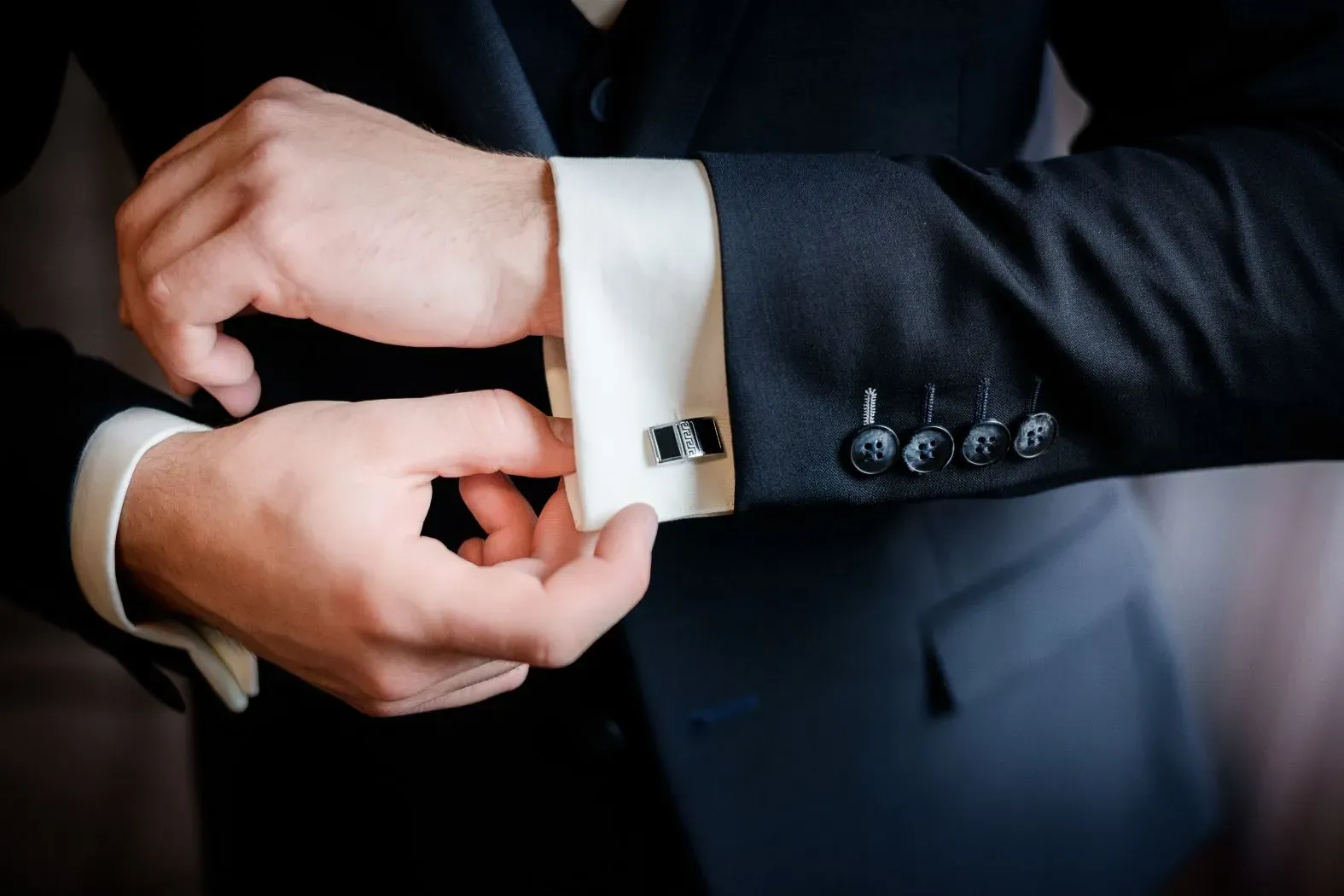 - Camisas a medida, novio en prueba de vestuario ajustando los detalles de puño de la camisa.