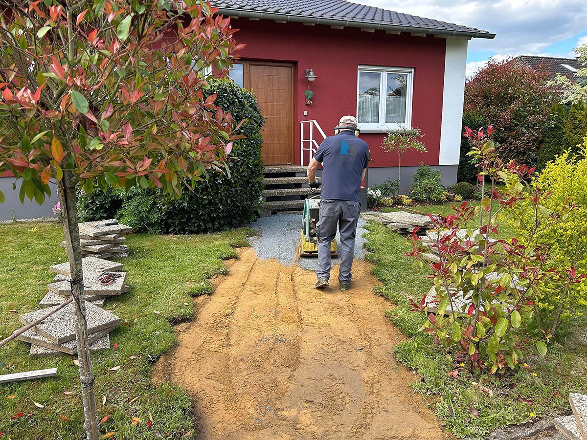 METZEN Objektservice Gartenweg pflastern Mitarbeiter mit Rüttelplatte