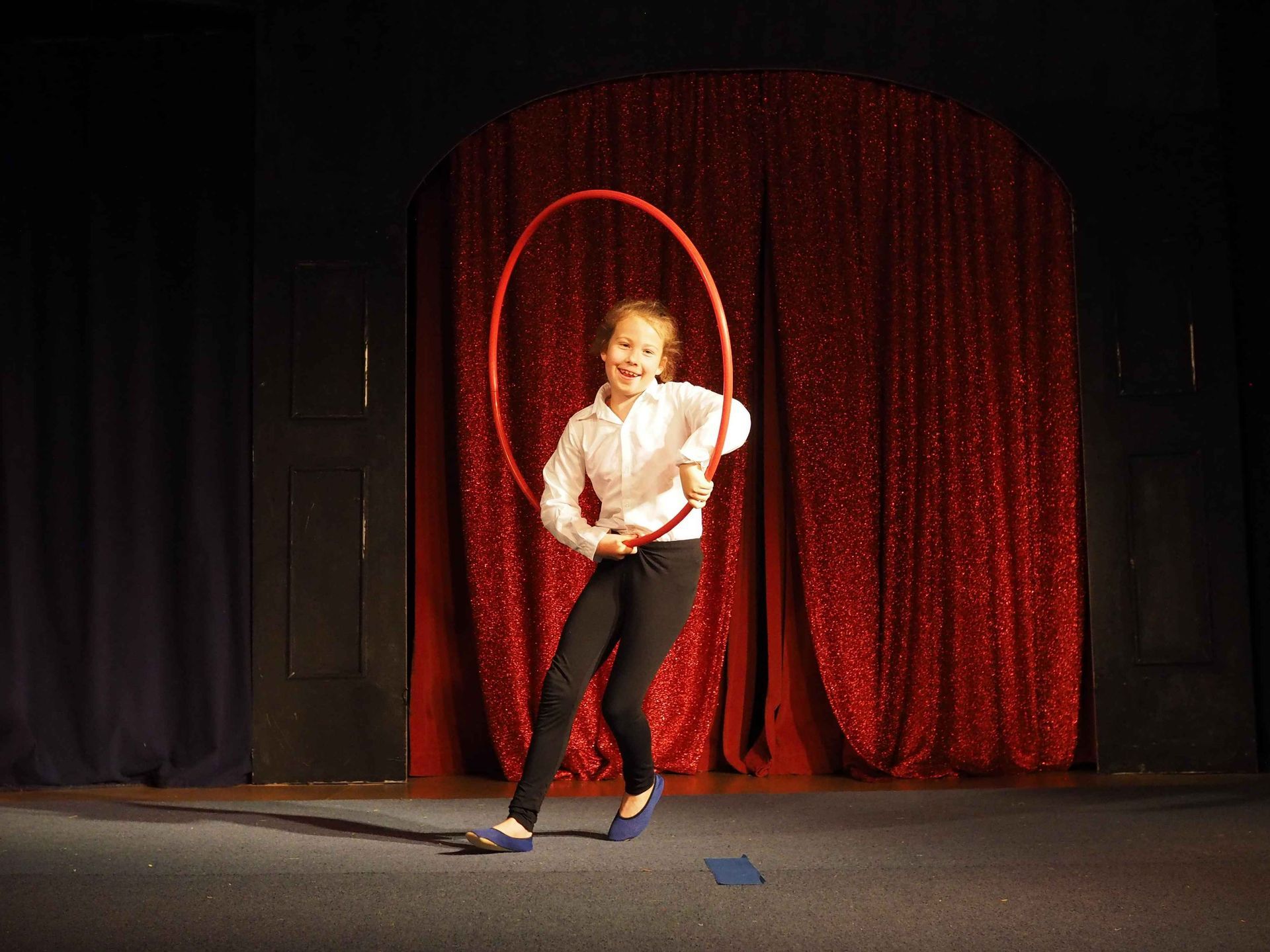 Im Zirkuszelt: eine Trainierende zeigt ein Kunststück mit dem Hulla-Hoop-Reifen.