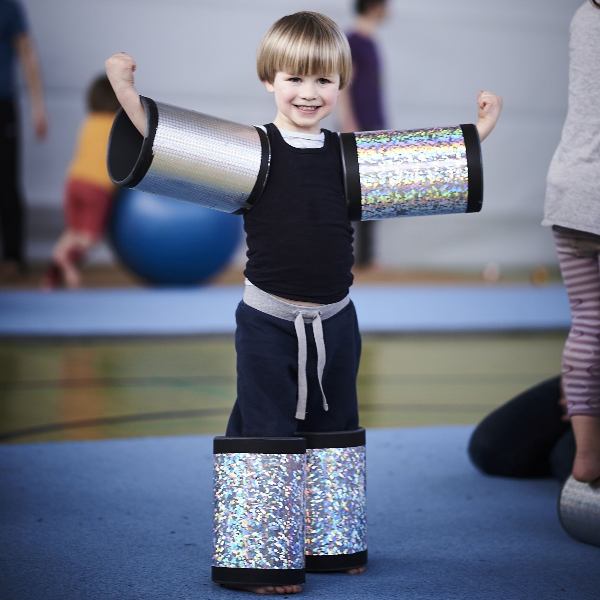 In der Turnhalle hat ein junger Trainierender die Rollen um Arme und Beine positioniert. Es sieht witzig aus.