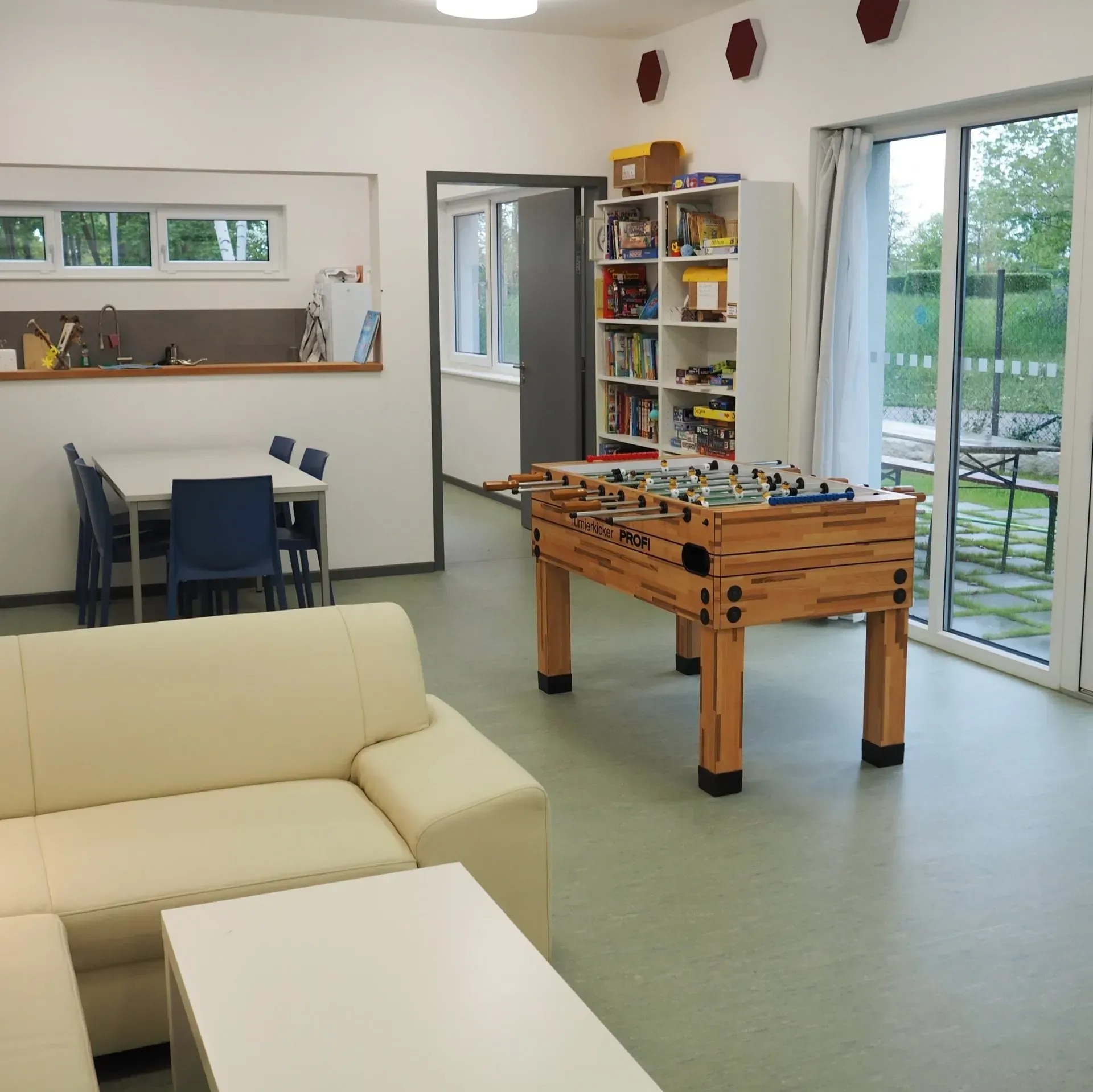 Der Freizeitraum des Zeltpunkts mit Kickertisch und , Couch und Bücherregal sind zu sehen.