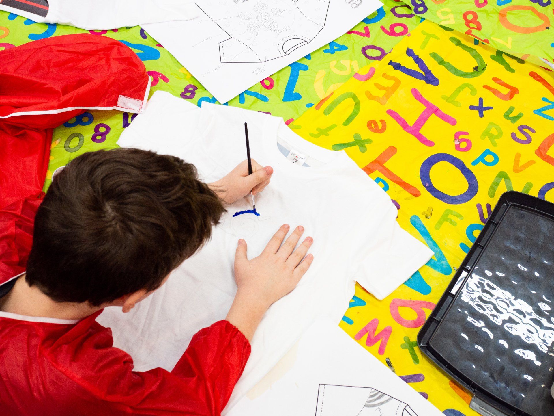 Boy customising t-shirt with paints