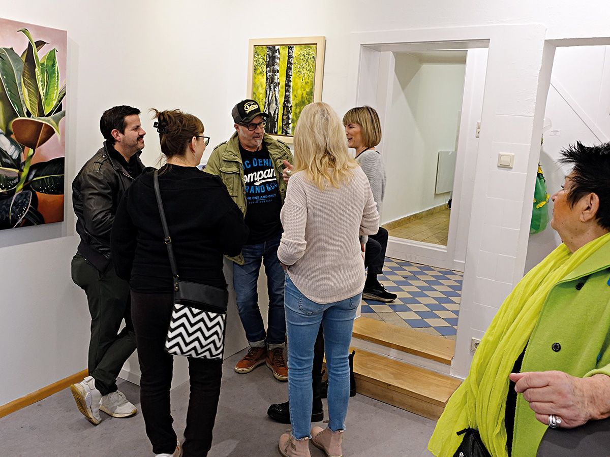 Eine Gruppe von Künstler*innen des Vereins in lebhaftem Gespräch, beobachtet von einer weiteren Künstlerin. Foto: Dieter Weißenberger