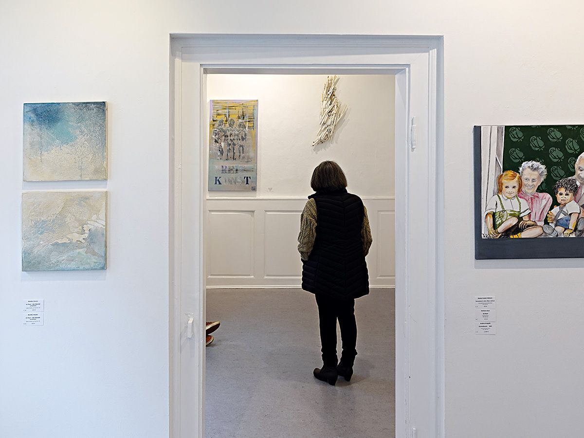 Eine Ausstellungsbesucherin steht im Durchgang zweier Ausstellungsräume und betrachtet die Kunstwerke an der rückseitigen Wand. Foto: Dieter Weißenberger