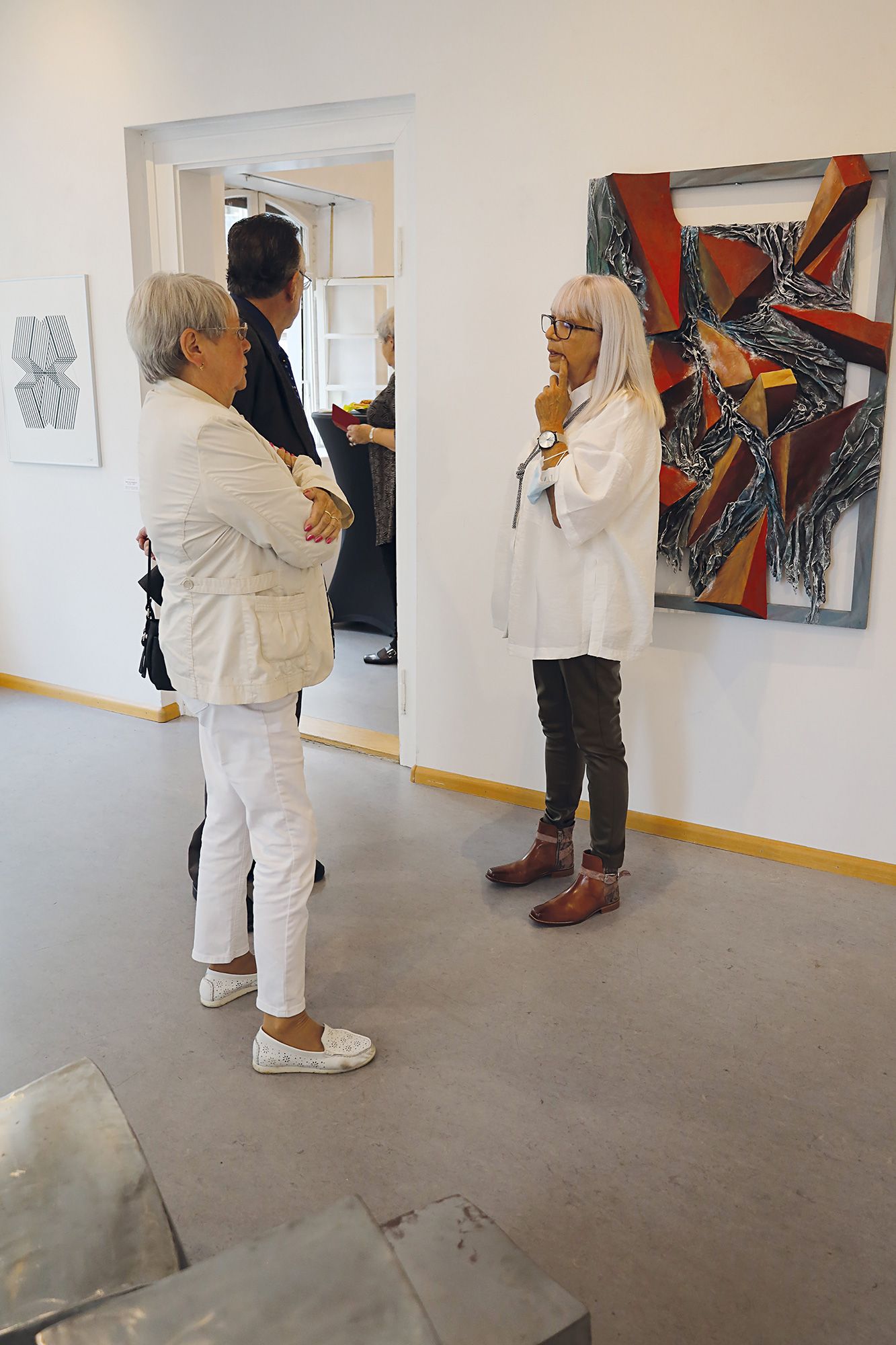 Ausstellungsbesucher im Gespräch. Im Hintergrund sind einige Kunstwerke zu sehen. Foto: Dieter Weißenberger