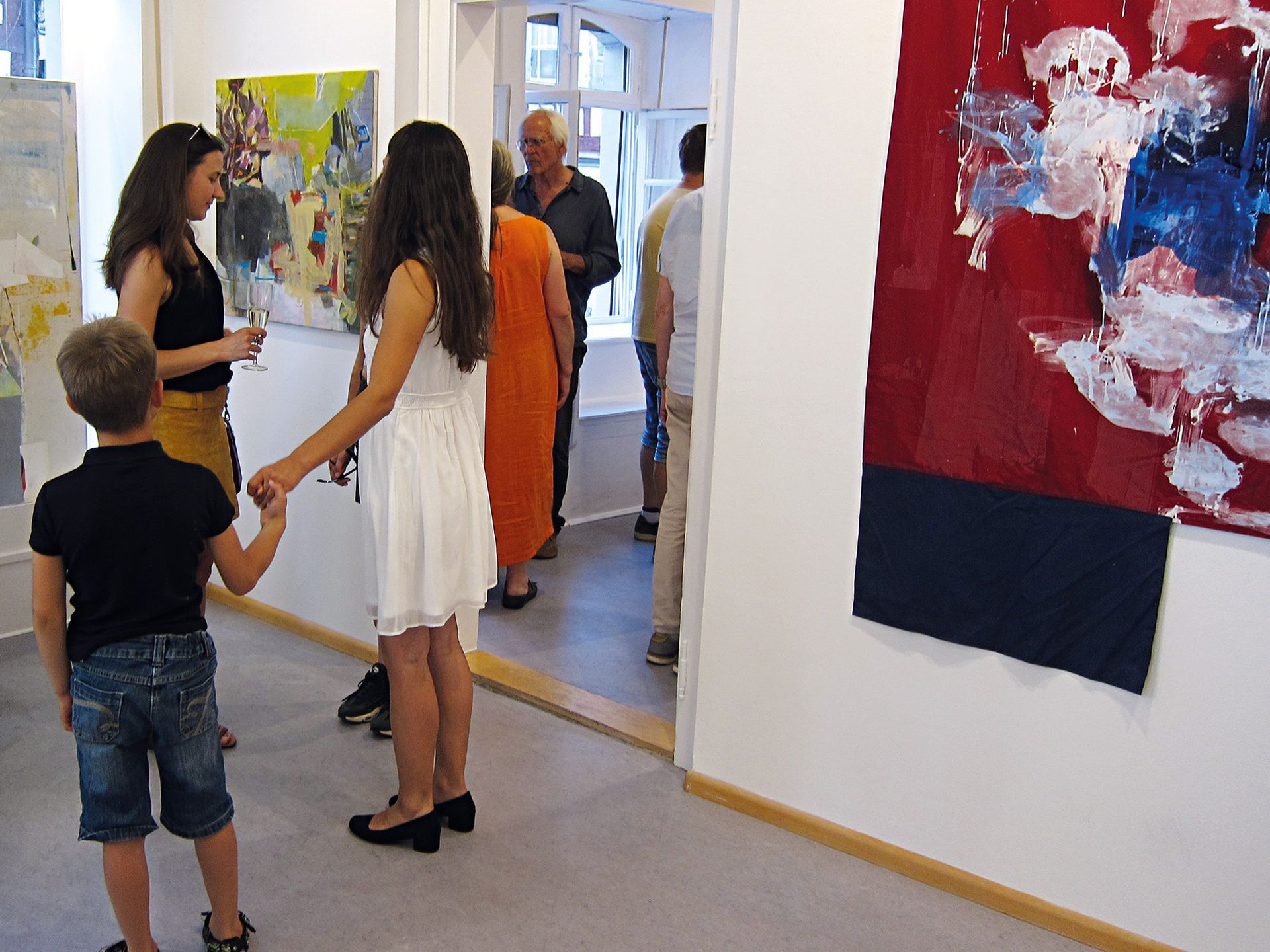 Vernissage in der Galerie mit Werken der Künstlerin Milena Wiedemer. Im Vordergrund zwei junge Frauen und ein Kind. Foto: Dieter Weißenberger