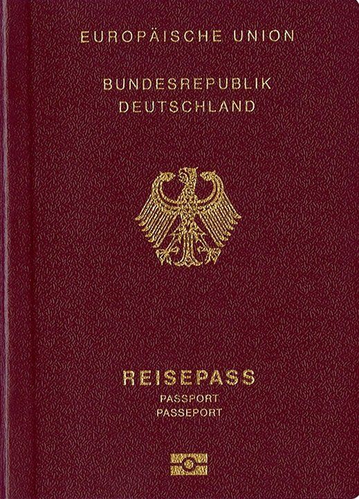 Person füllt Antragsformular für deutschen Reisepass aus, mit notwendigen Dokumenten und einem Passfoto auf einem Tisch