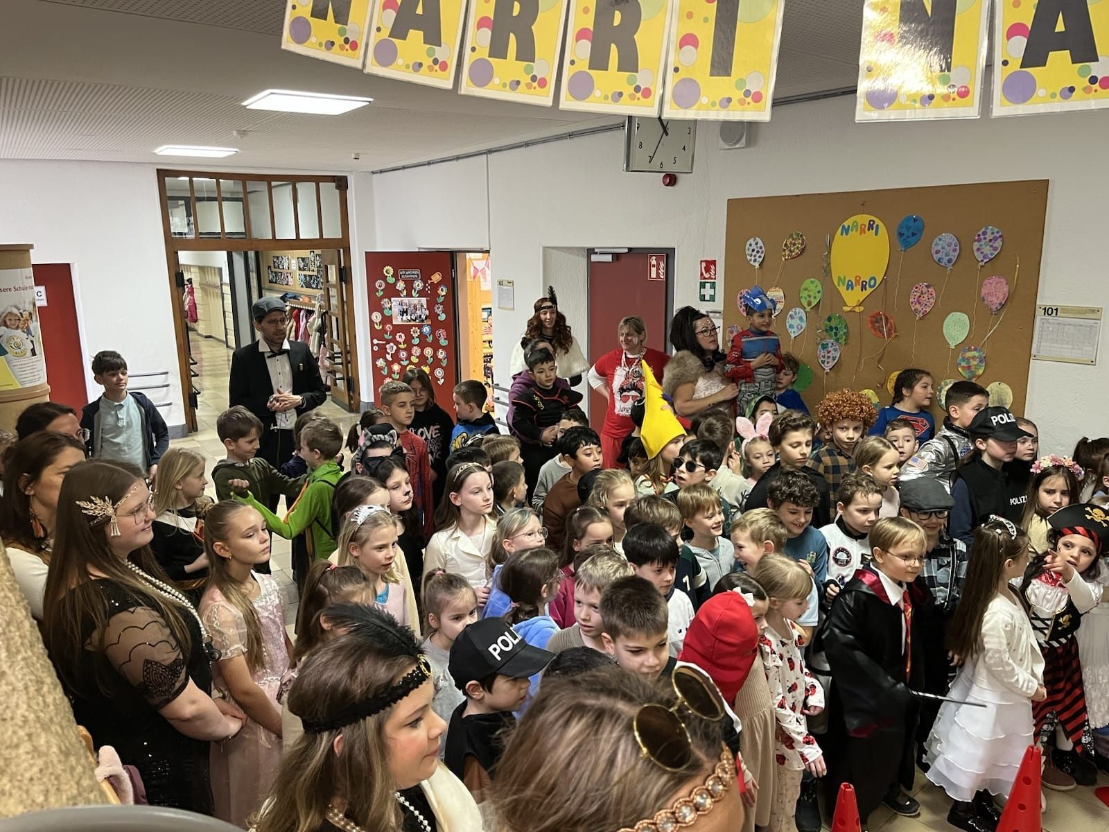 Verkleide Kinder und Lehrkräfte schauen einer Aufführung zu