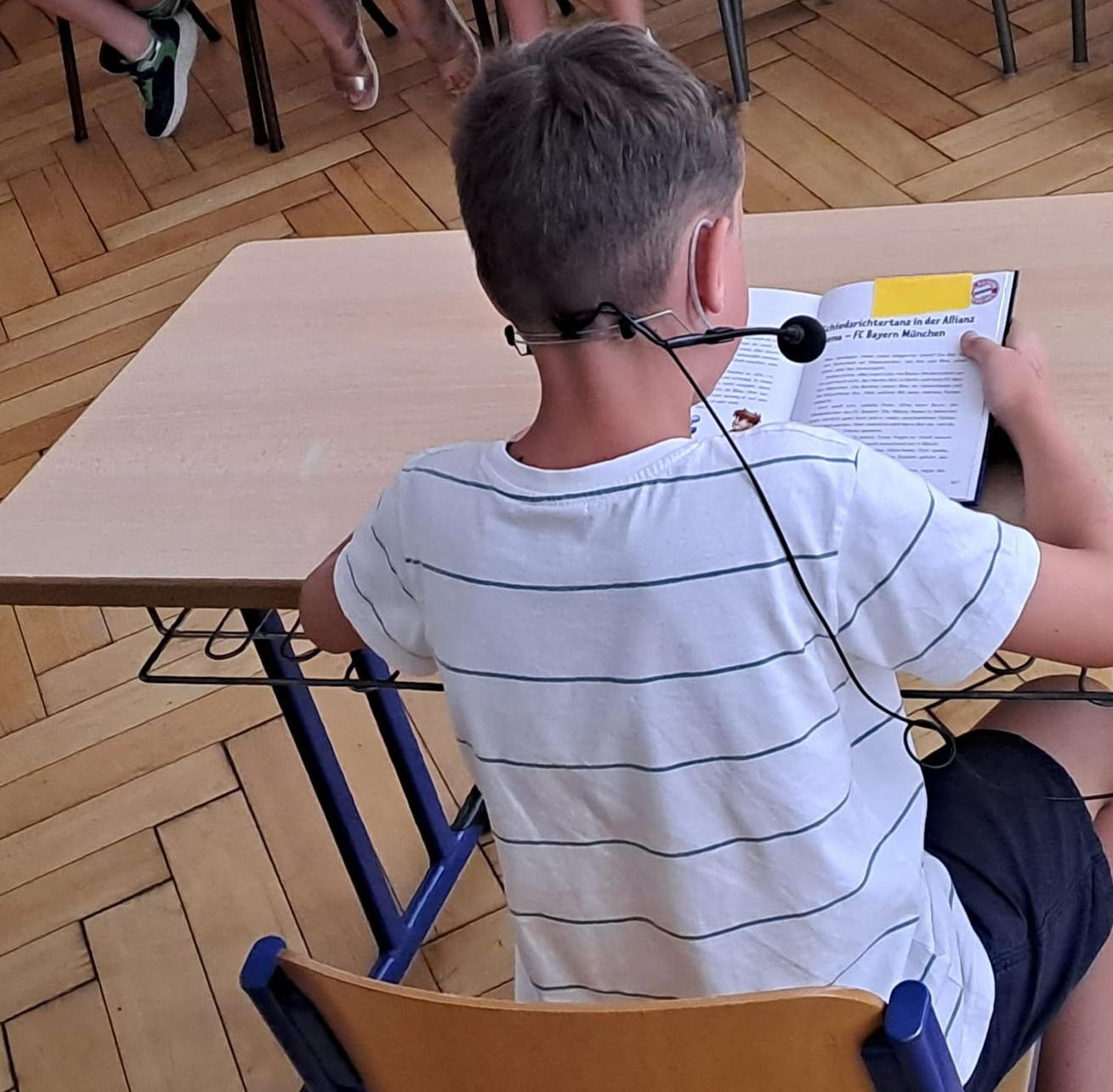 Junge von hinten, der aus seinem Buch vorliest.