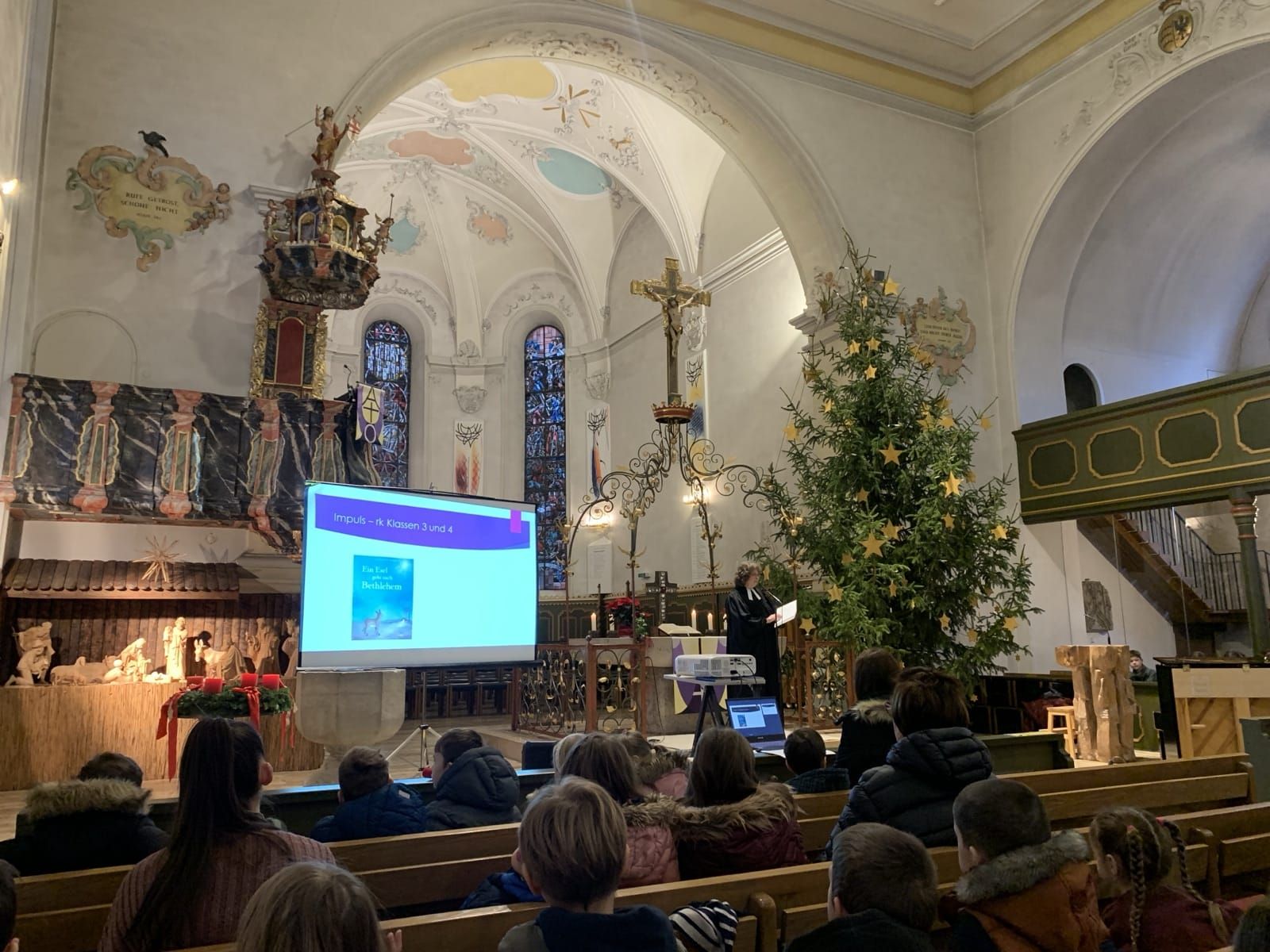 Blick auf den Altarbereich mit geschmücktem Tannenbaum.