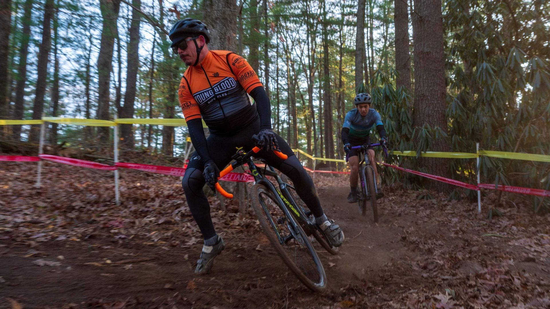 two bike racers ride their bikes through the woods