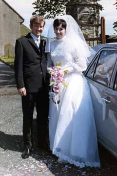 Bride and groom posing beside a car. After restoration