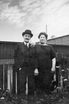 Restored black and white photo of a couple standing together in front of a wooden fence.