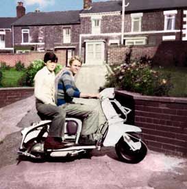 Restored and colourised photo of two lads on a scooter in front of houses
