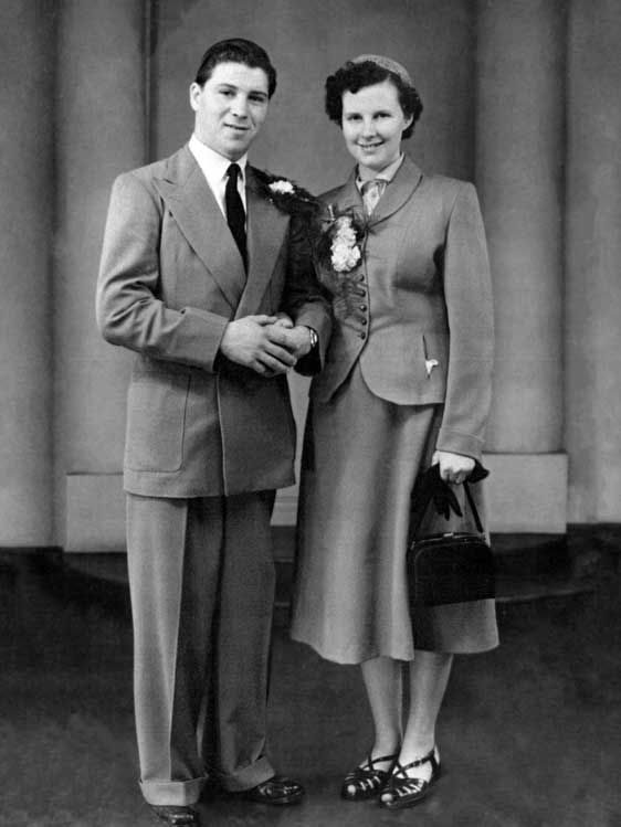 Restored photo of a couple standing together in wedding suits.