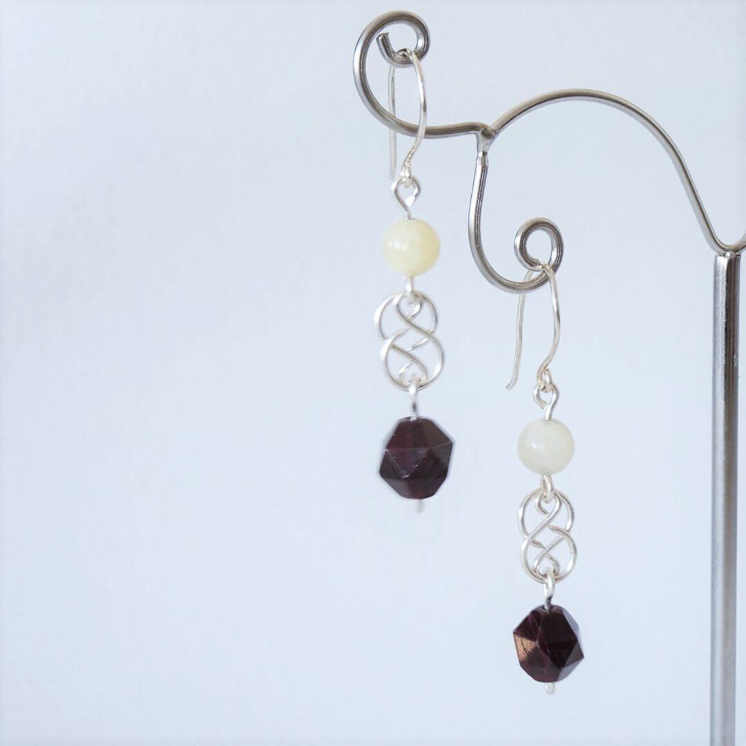 Cette photo représente des boucles d'oreilles en argent, aragonite et grenat par Nathalyne.