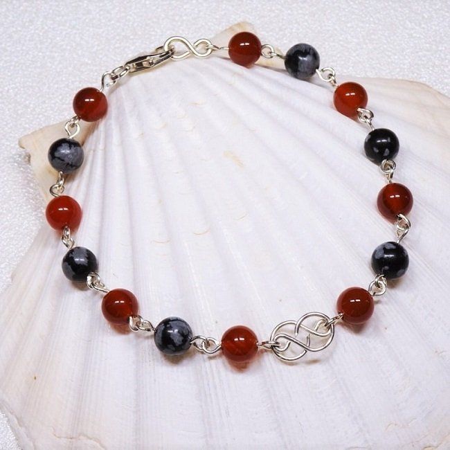 Cette image représente un bracelet en cornaline et obsidienne neige sur argent massif par Nathalyne. Ces pierres permettent de surmonter la colère.