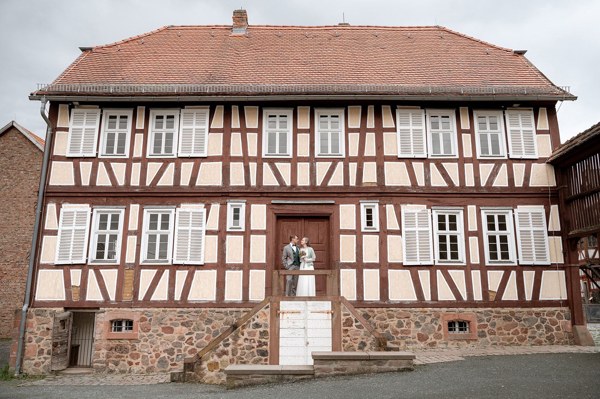 Niklas und Annika schauen sich während des Fotoshootings tief in die Augen, die beiden stehen auf einer Empore vor einem historischen Fachwerkhaus im Hessenpark