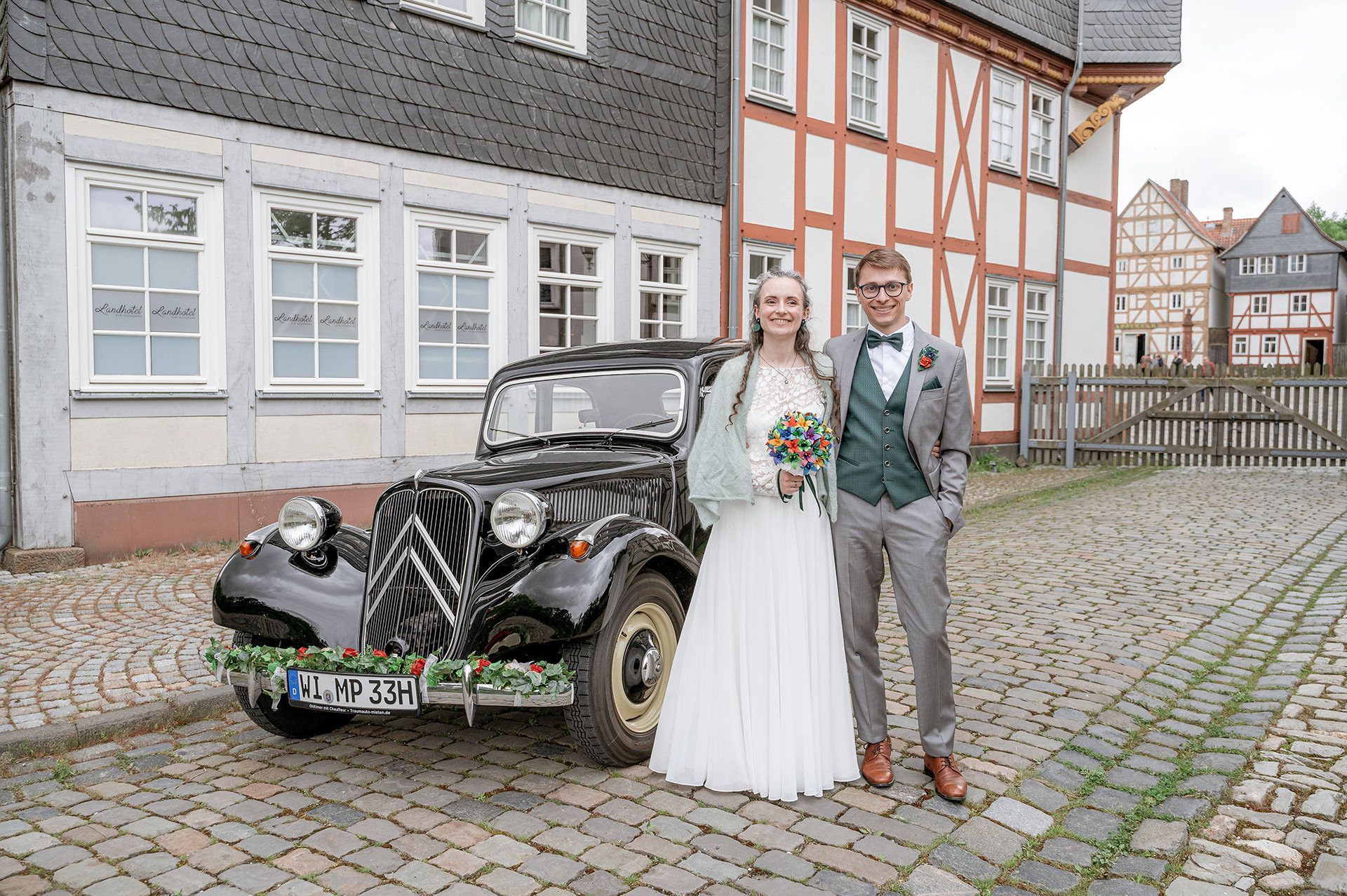 Das Brautpaar posiert vor ihren Hochzeitsauto im Hessenpark in Neu-Anspach