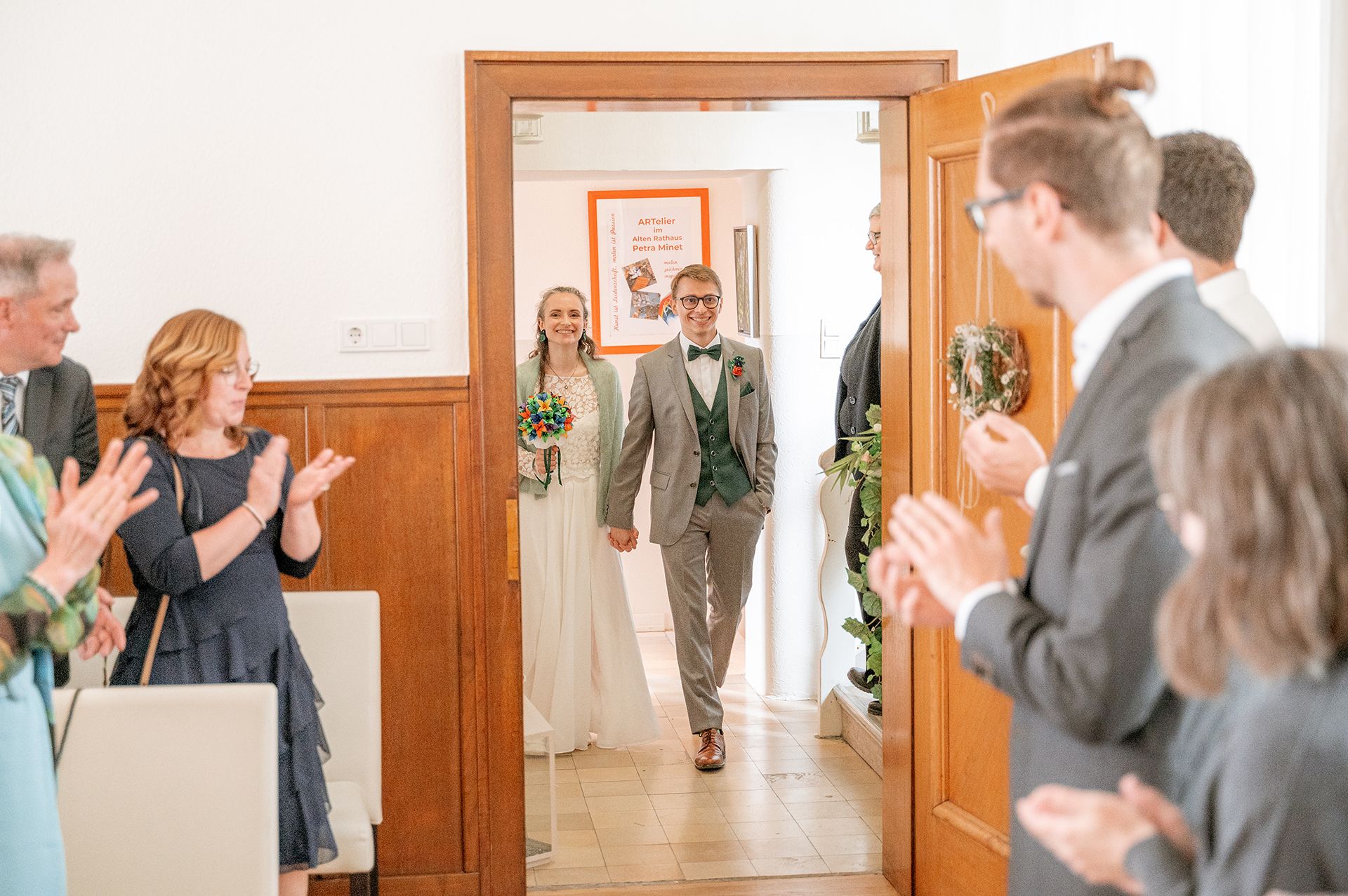 Das Brautpaar Niklas und Annika schreitet im Standesamt Wehrheim den Gang entlang, während die Gäste begeistert applaudieren.