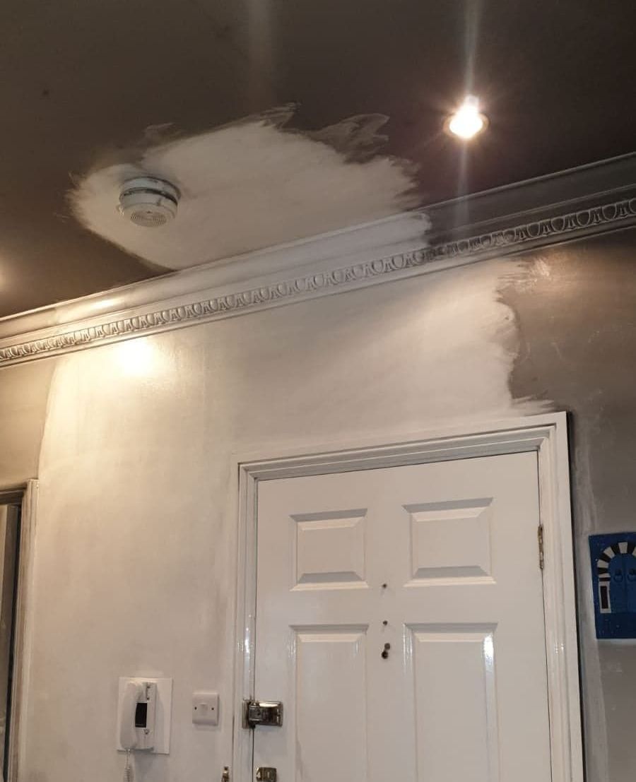 A ceiling with distinct discoloration caused by cigarette smoke damage. The upper half of the ceiling appears yellowed, while the lower half remains white. A noticeable cleaning effort has been made on the lower half, which now appears cleaner and brighter