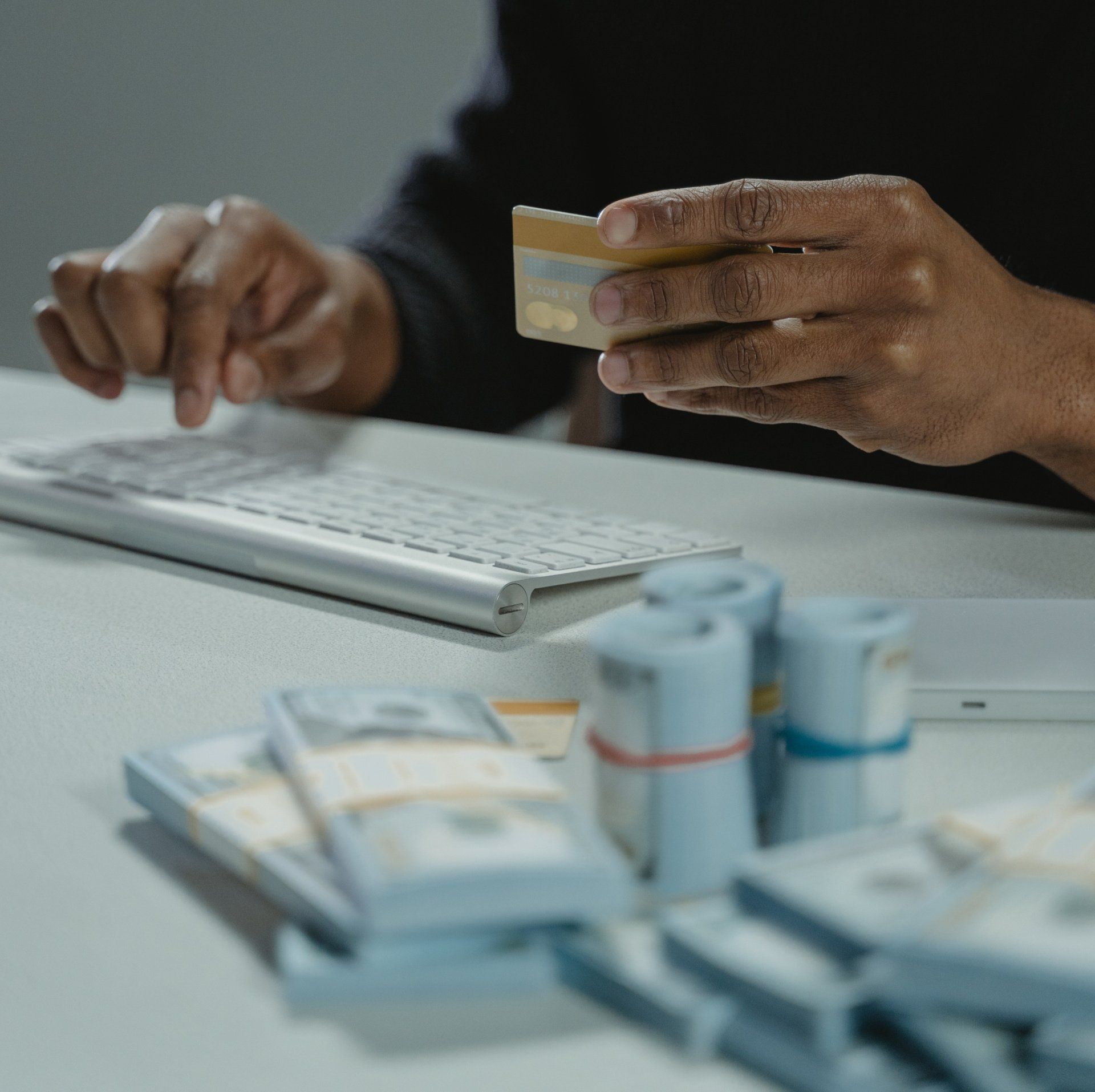 Money on the table and man using a card to pay for something on the computer