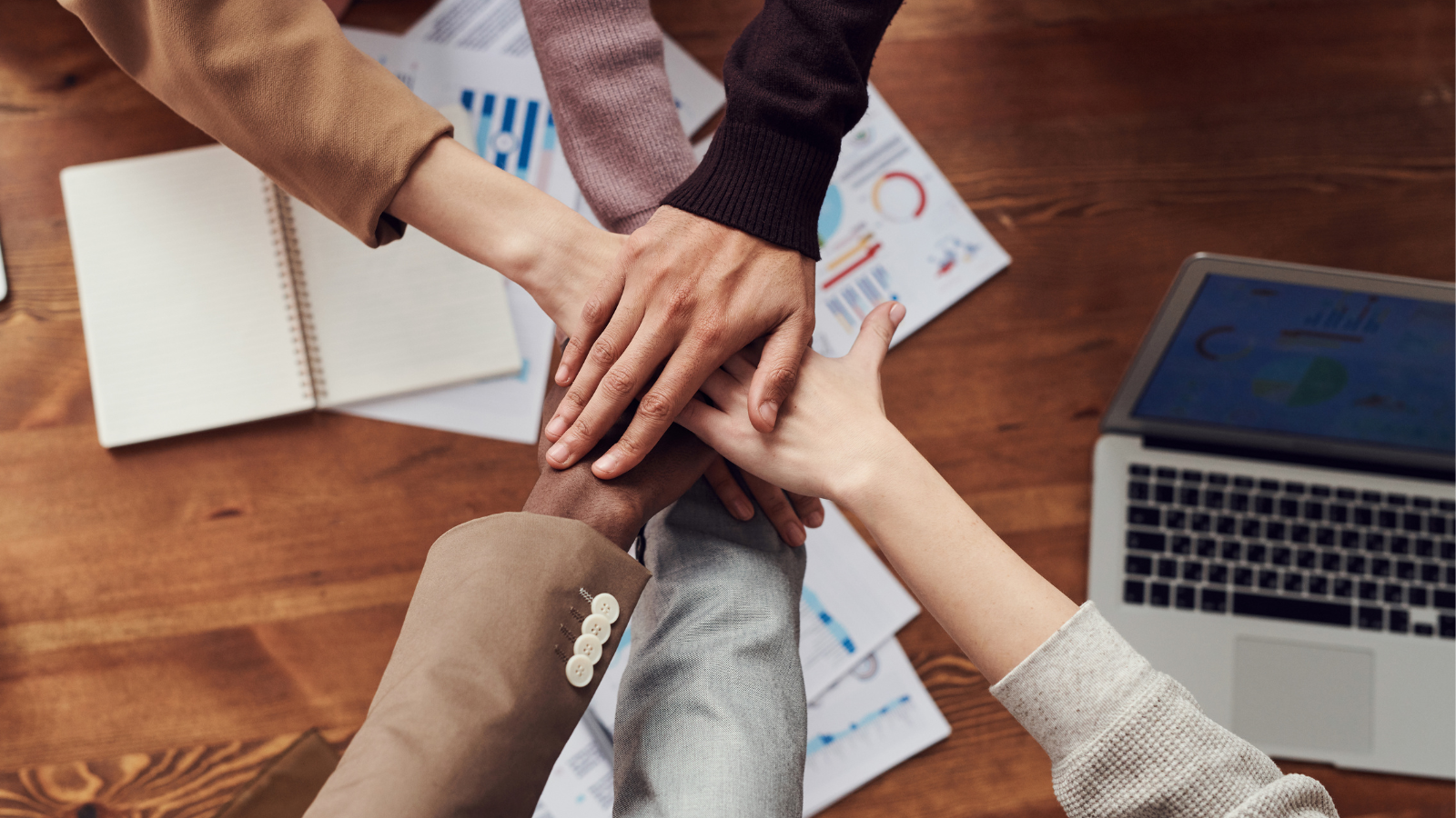 Multicultural fractional team piling hands in pow-wow.
