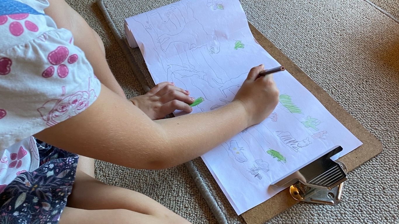 A child sits and draws on a long strip of paper, the timeline of life.