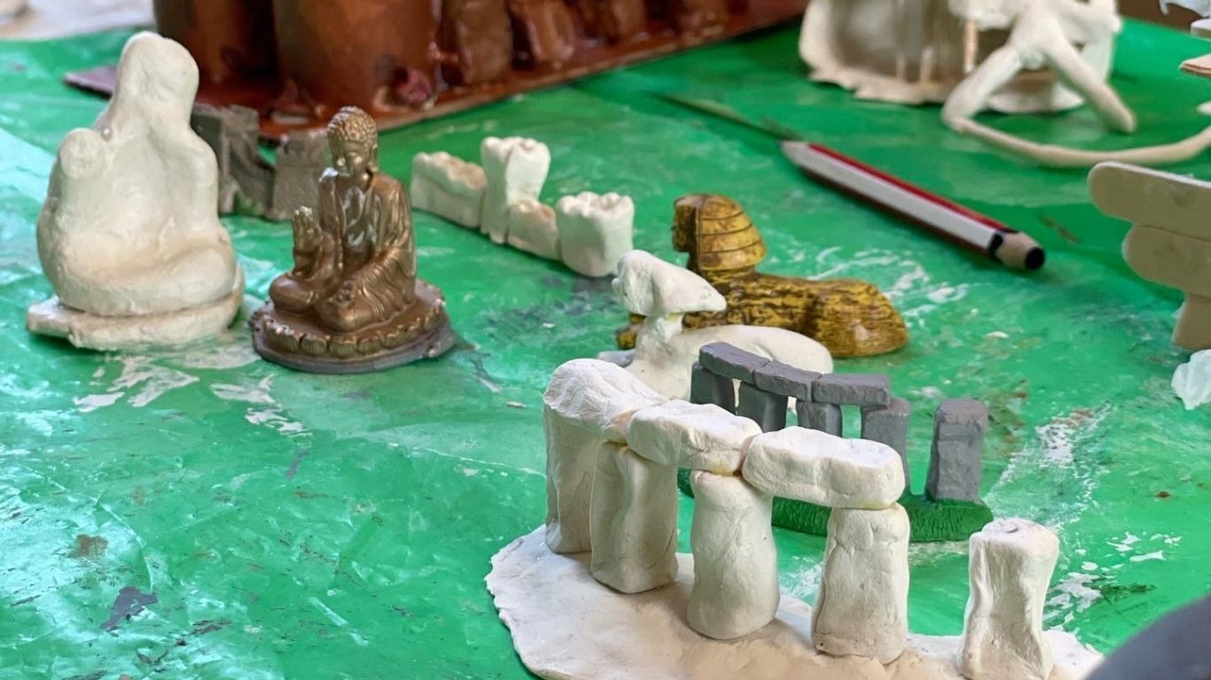 Tonmodelle einiger der 7 Weltwunder der Antike stehen inmitten ihrer Miniaturinspirationen. Da stehen die Buddha-Statue, Stonehenge und die Sphinx.