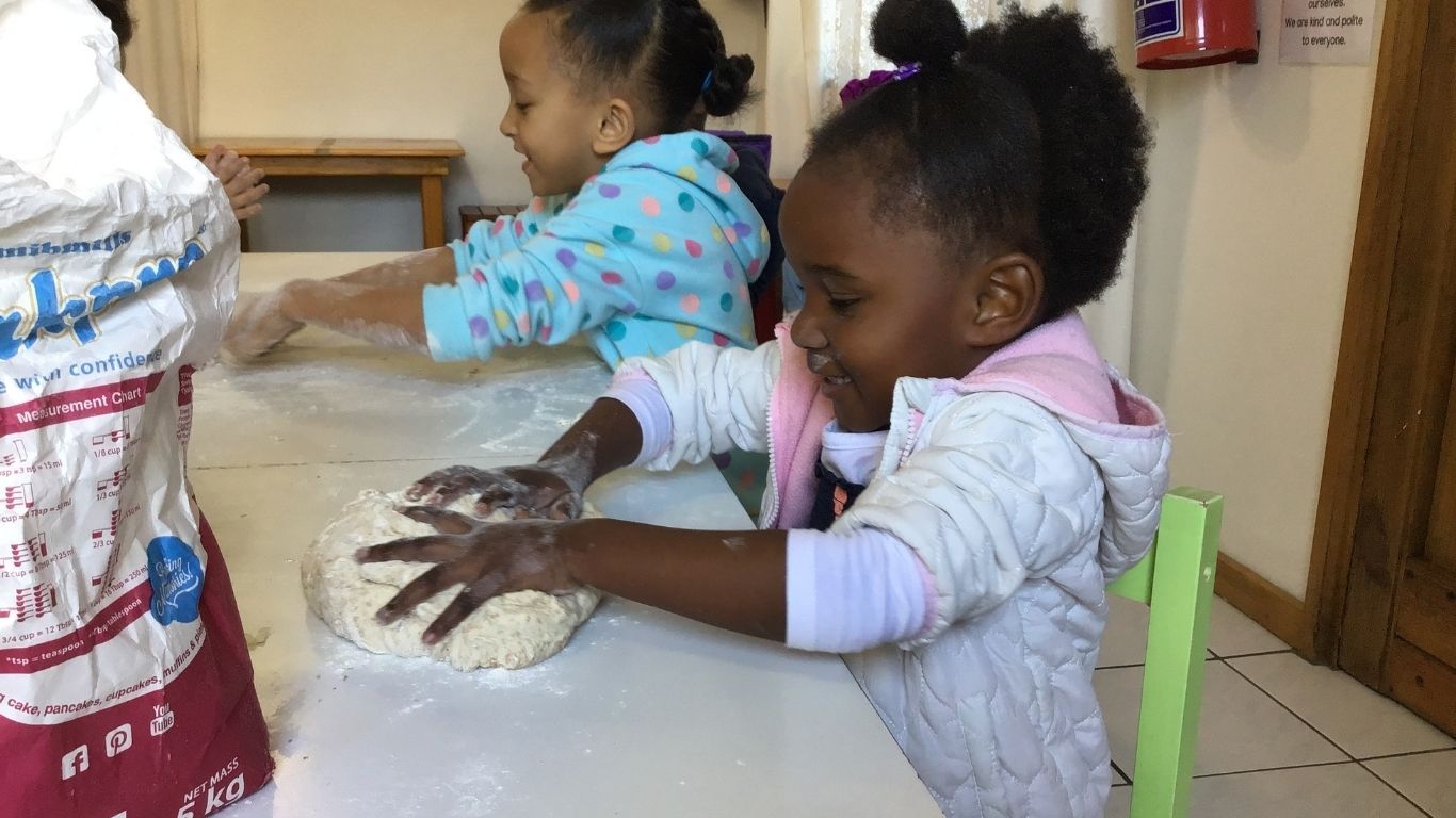 Kinder backen glücklich Brot.