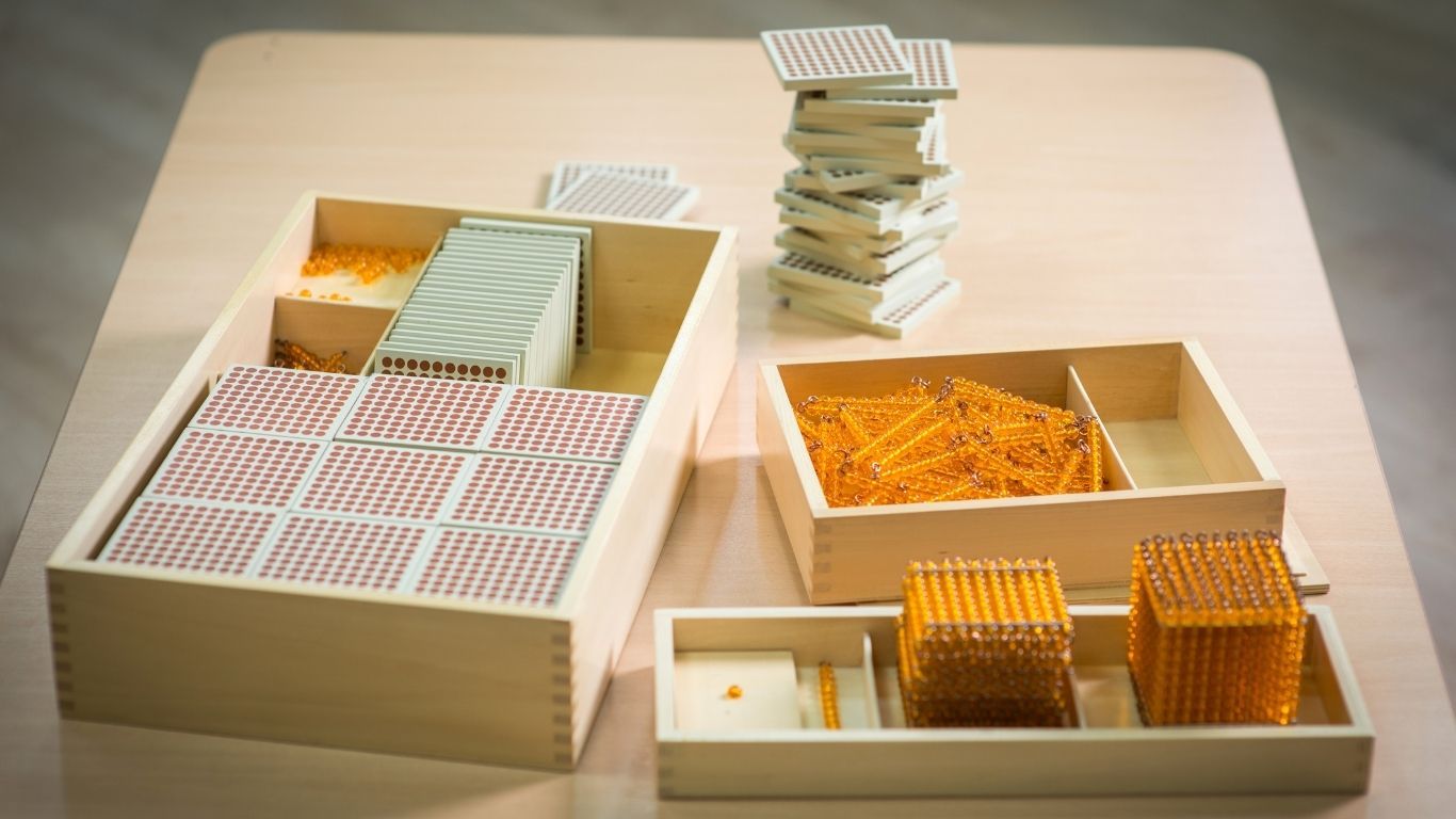 Goldene Perlen der Montessori-Didaktik liegen auf einem Tisch.